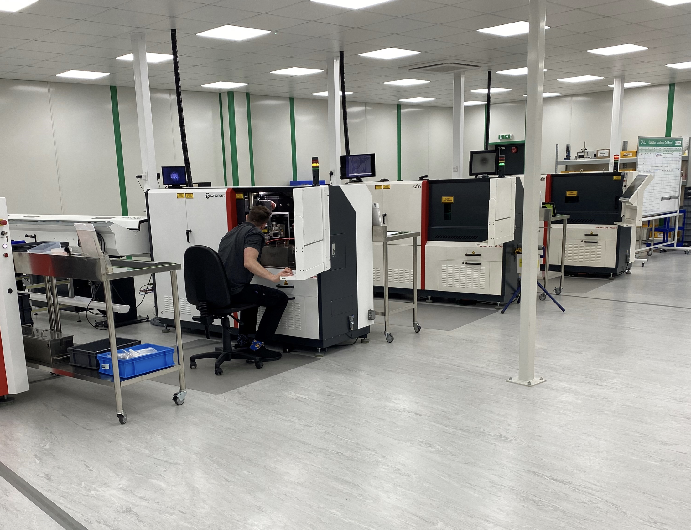 Technician operating advanced manufacturing equipment for precision medical device component production.