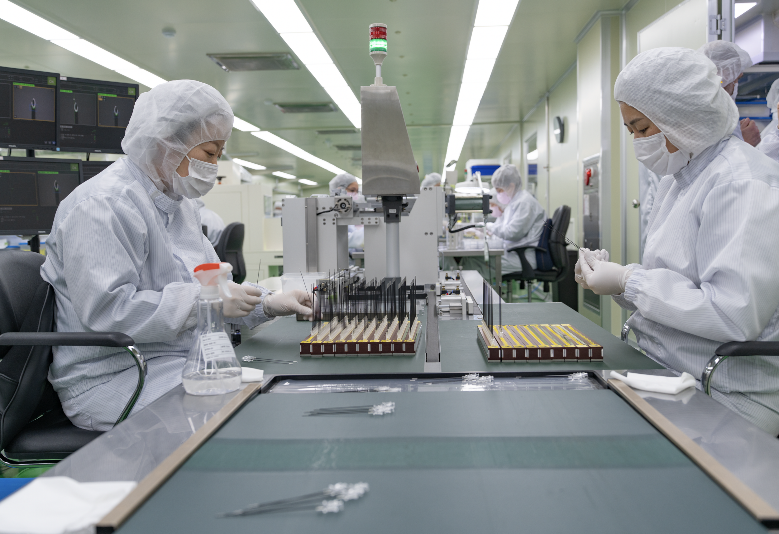 Technicians working with precision manufacturing equipment in a controlled cleanroom environment for medical device production.