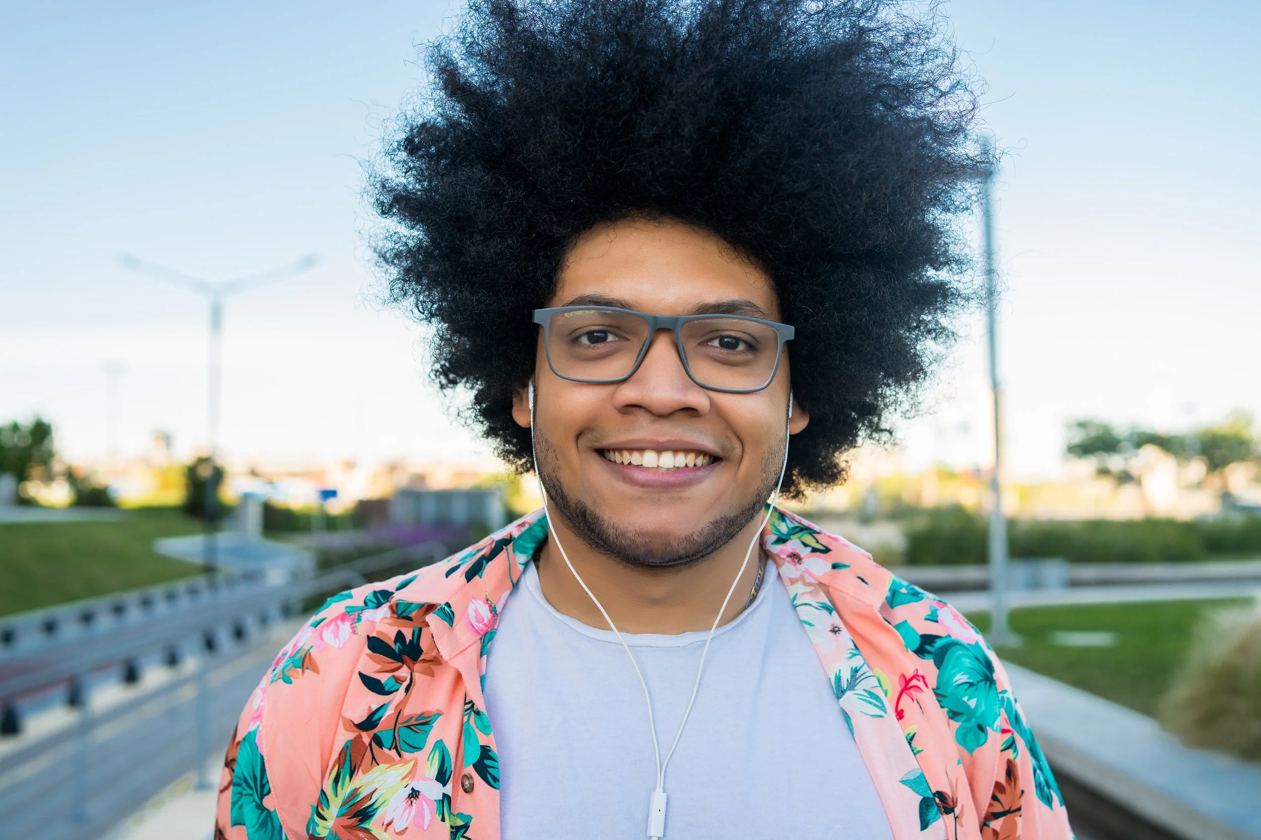 Image of a confident young man smiling outdoors, symbolizing self-assurance, personal growth, and culturally attuned mental health support