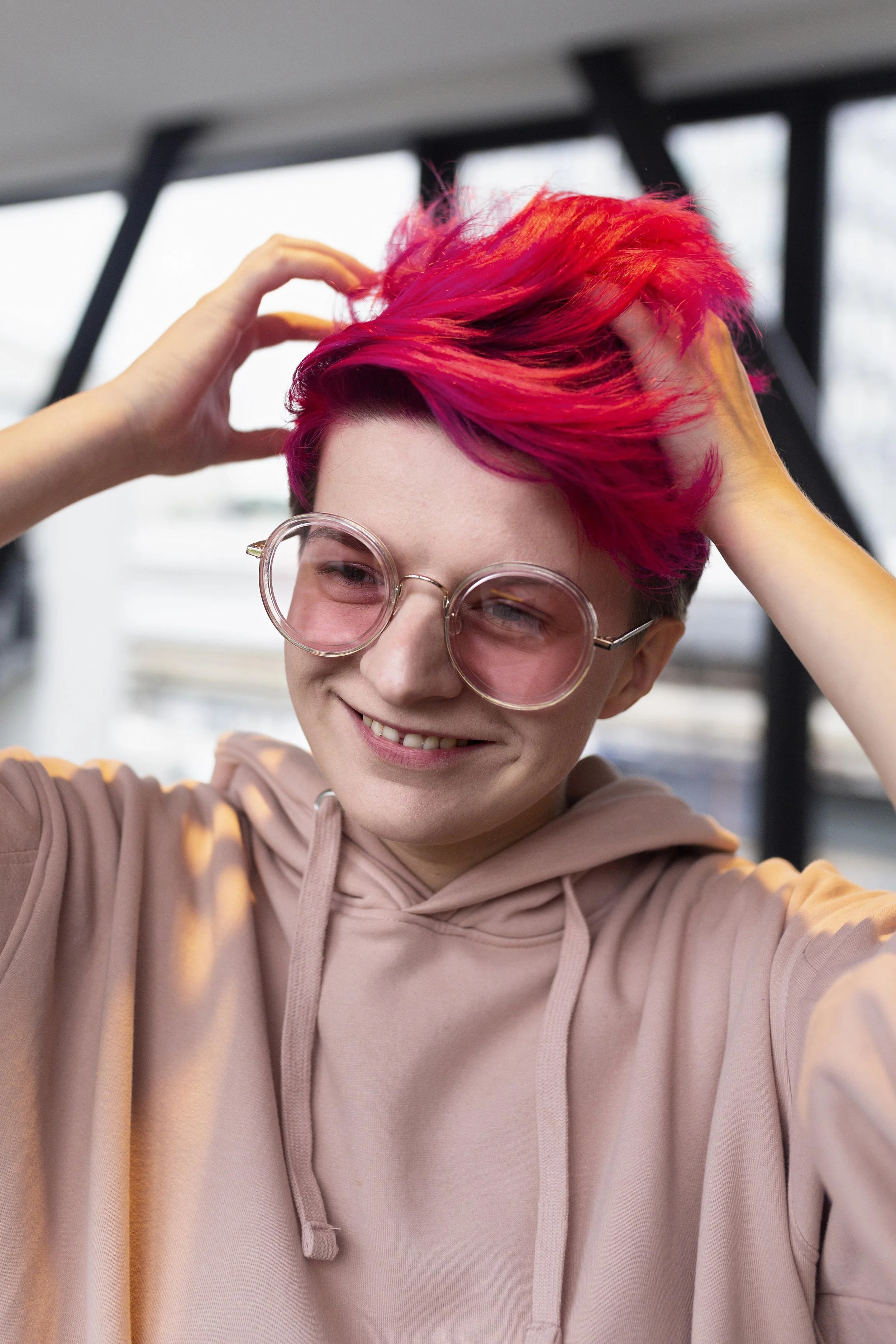 Image of a smiling teenager with pink hair—representing self-expression, individuality, and the inclusive, identity-affirming nature of online mental health support
