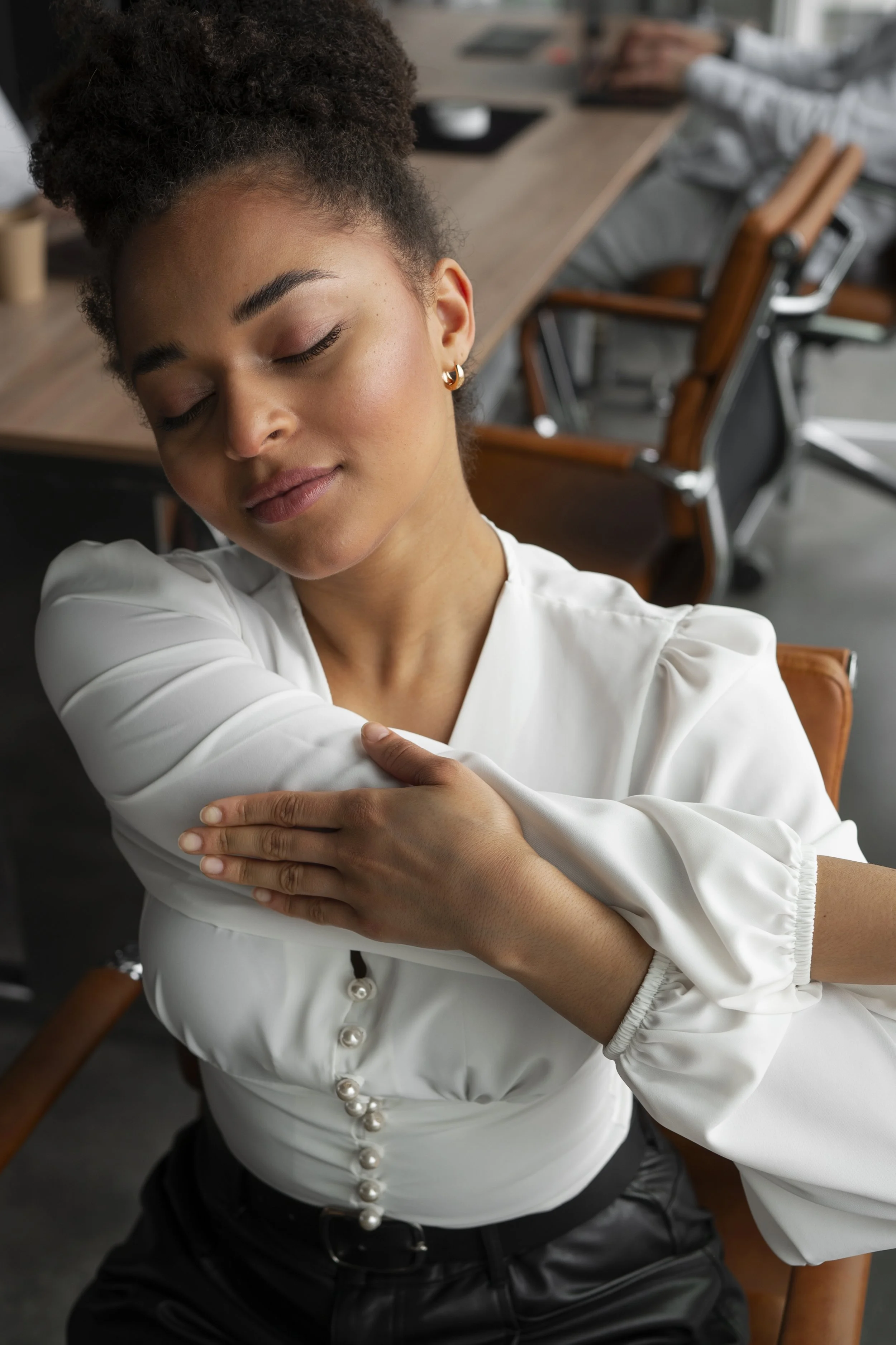 Woman stretching at her desk and smiling after practicing pain-relief techniques taught by clinicians at Guidance Teletherapy’s Empowered Relief program