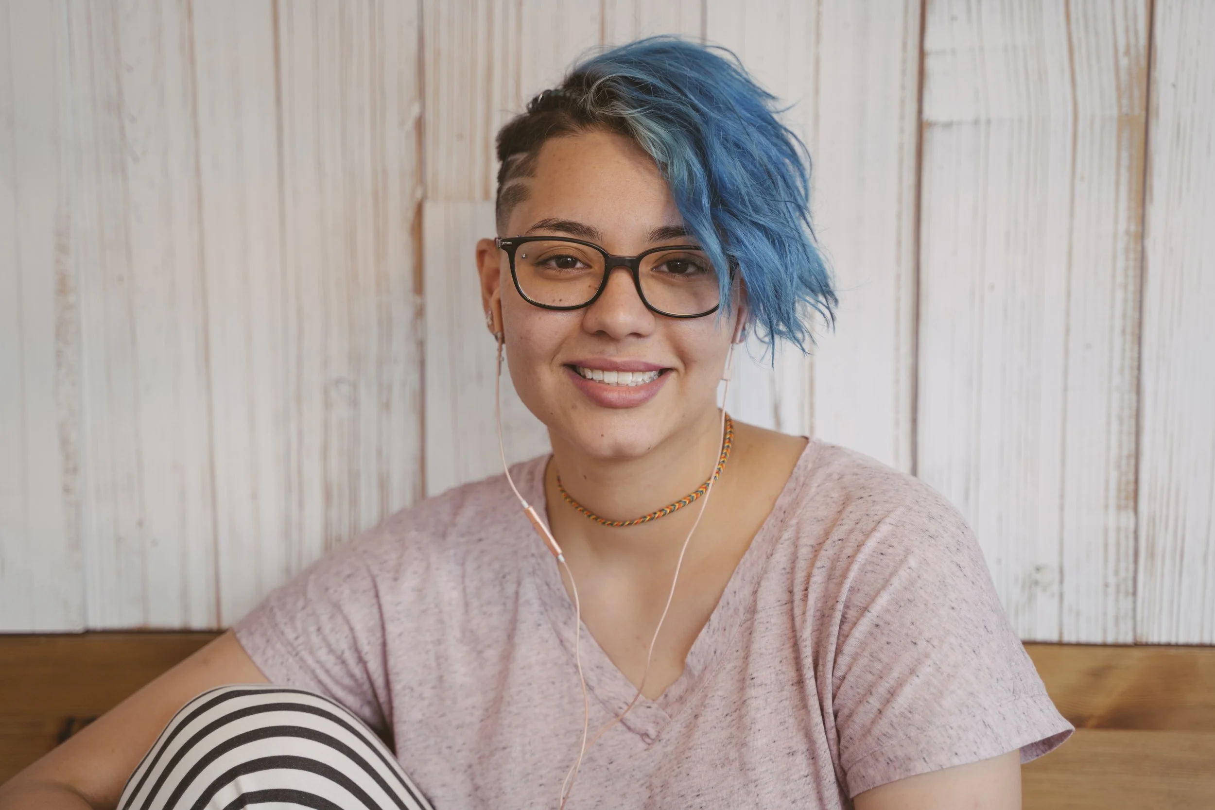 Image of a smiling young woman wearing earbuds, representing personalized support and accessible online therapy services at Guidance Teletherapy