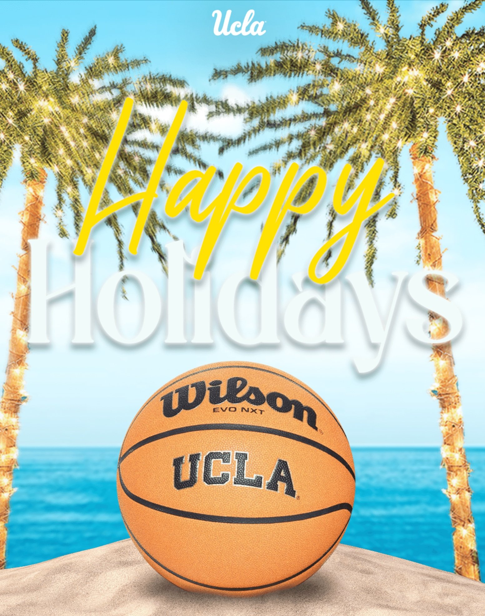 Beach scene with a UCLA-branded basketball on sand, palm trees with lights, blue ocean, sky, and "Happy Holidays" text.
