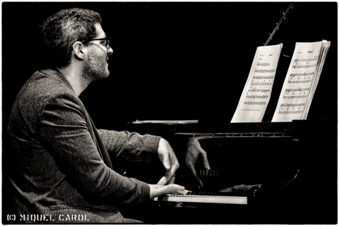 Musician playing piano with sheet music, side profile view