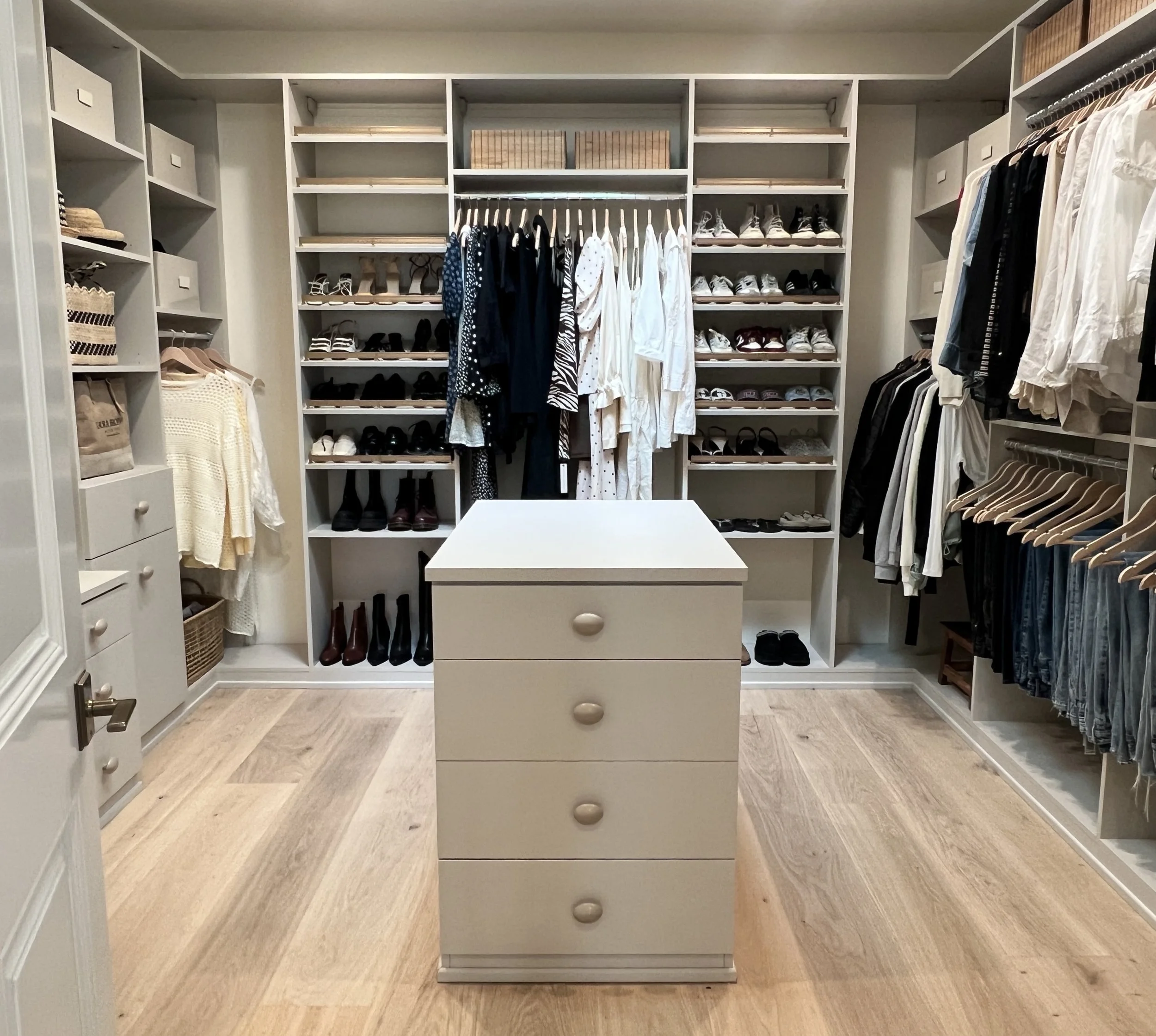Luxury walk-in closet organized in Beverly Hills, CA with color-coded clothing, shelves, and modern drawer island