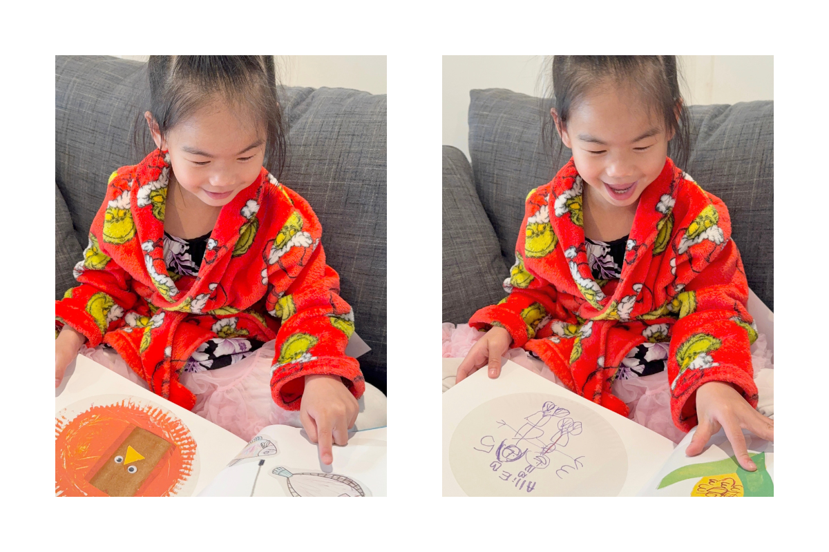 Young child smiling while looking through a custom book of their artwork created with Artkive