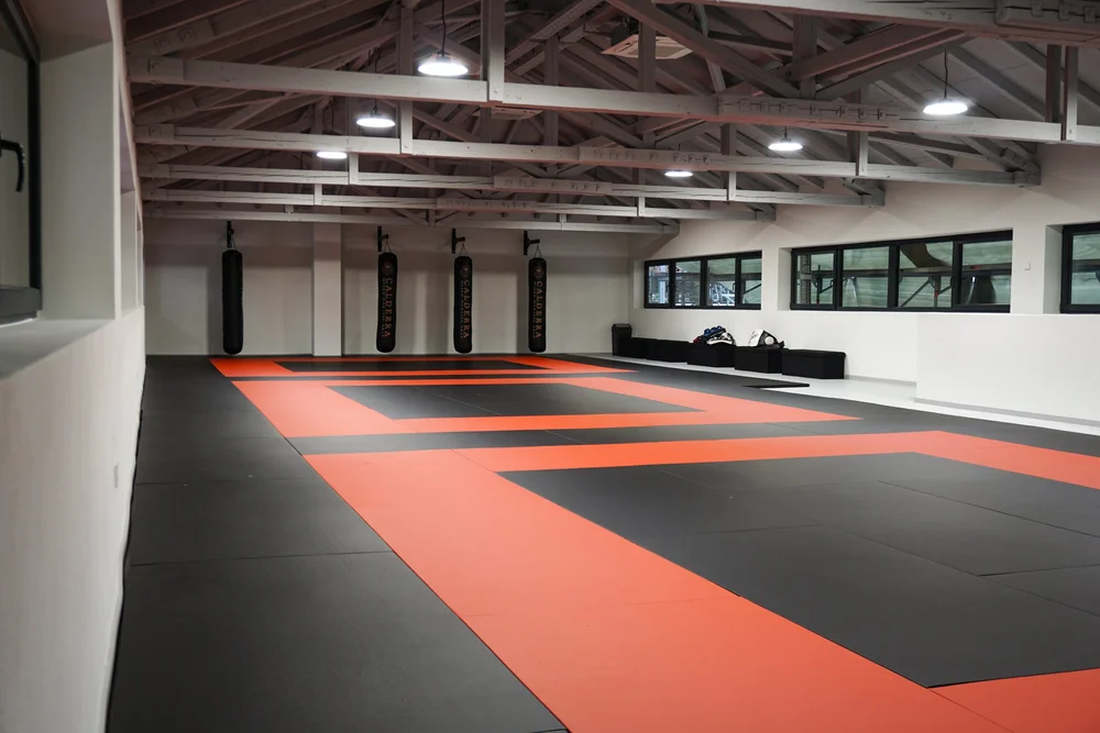 Trainingshalle von Calderra MMA in Ludwigsburg mit schwarz-orangen Matten und Sandsäcken