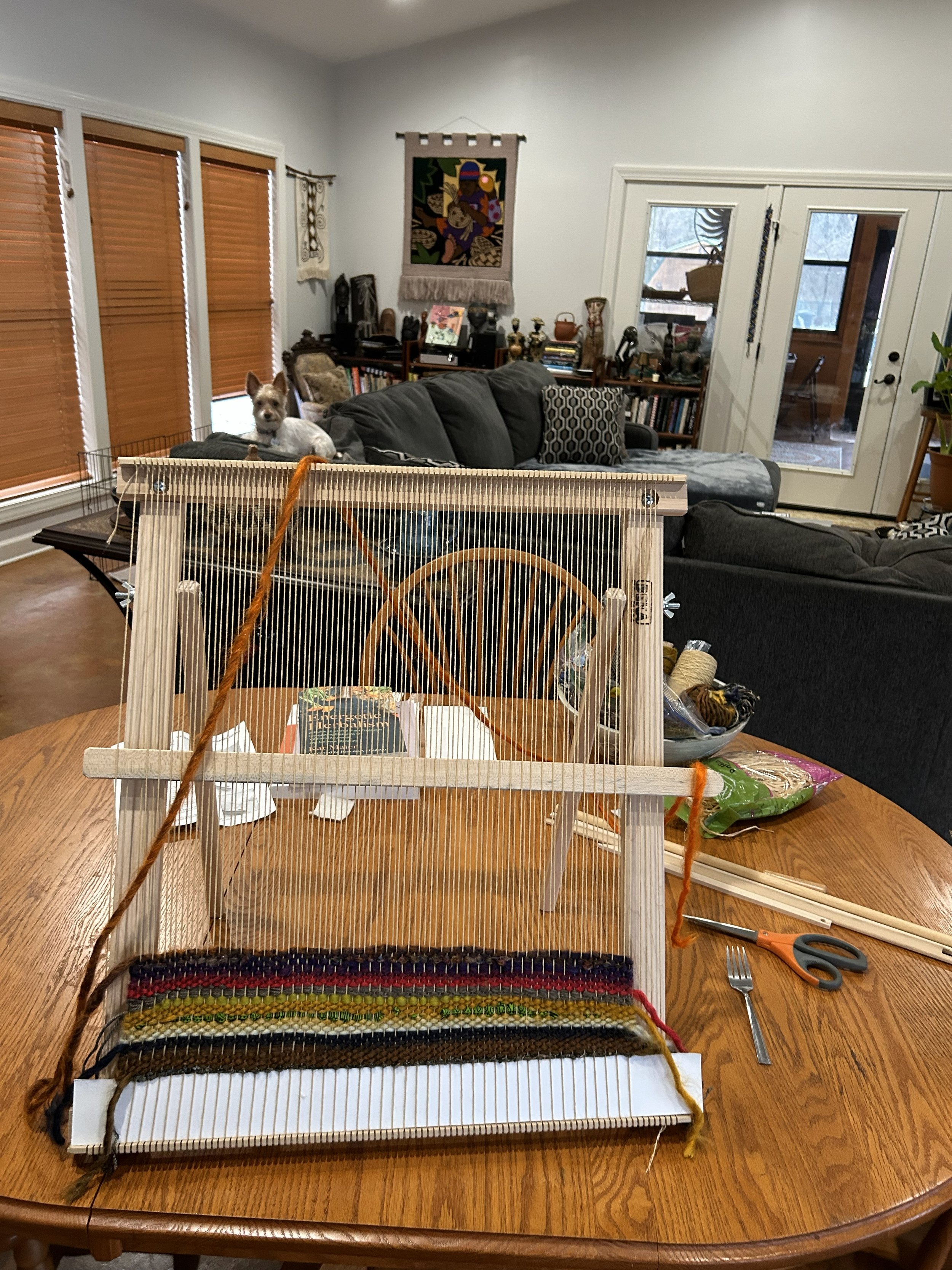 table top loom Emi looking on.jpeg