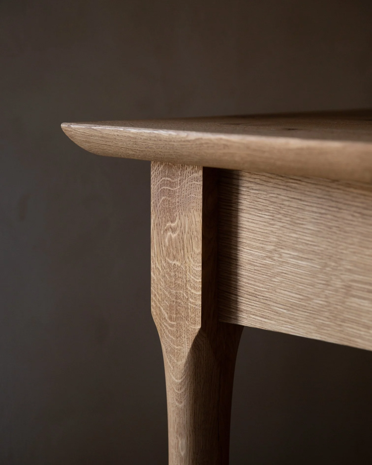 Close-up of a wooden table's corner and leg, showing natural wood grain and smooth finish.