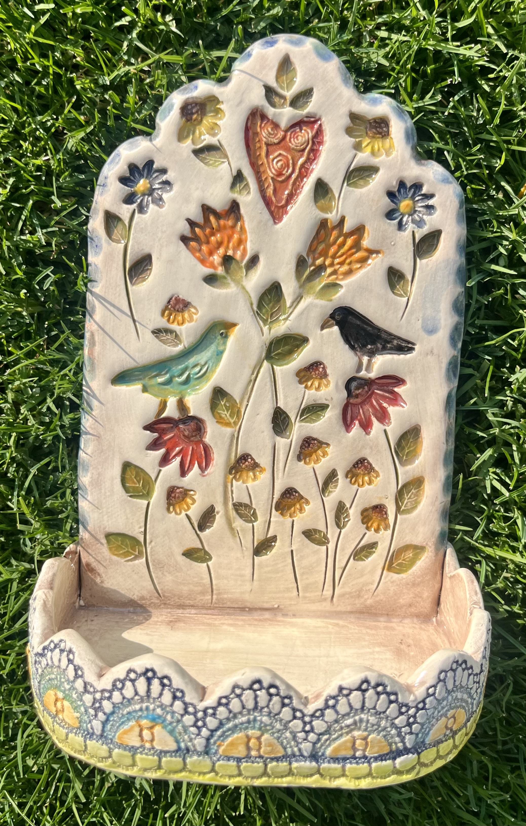 Decorative ceramic wall piece with embossed flowers, birds, and heart design