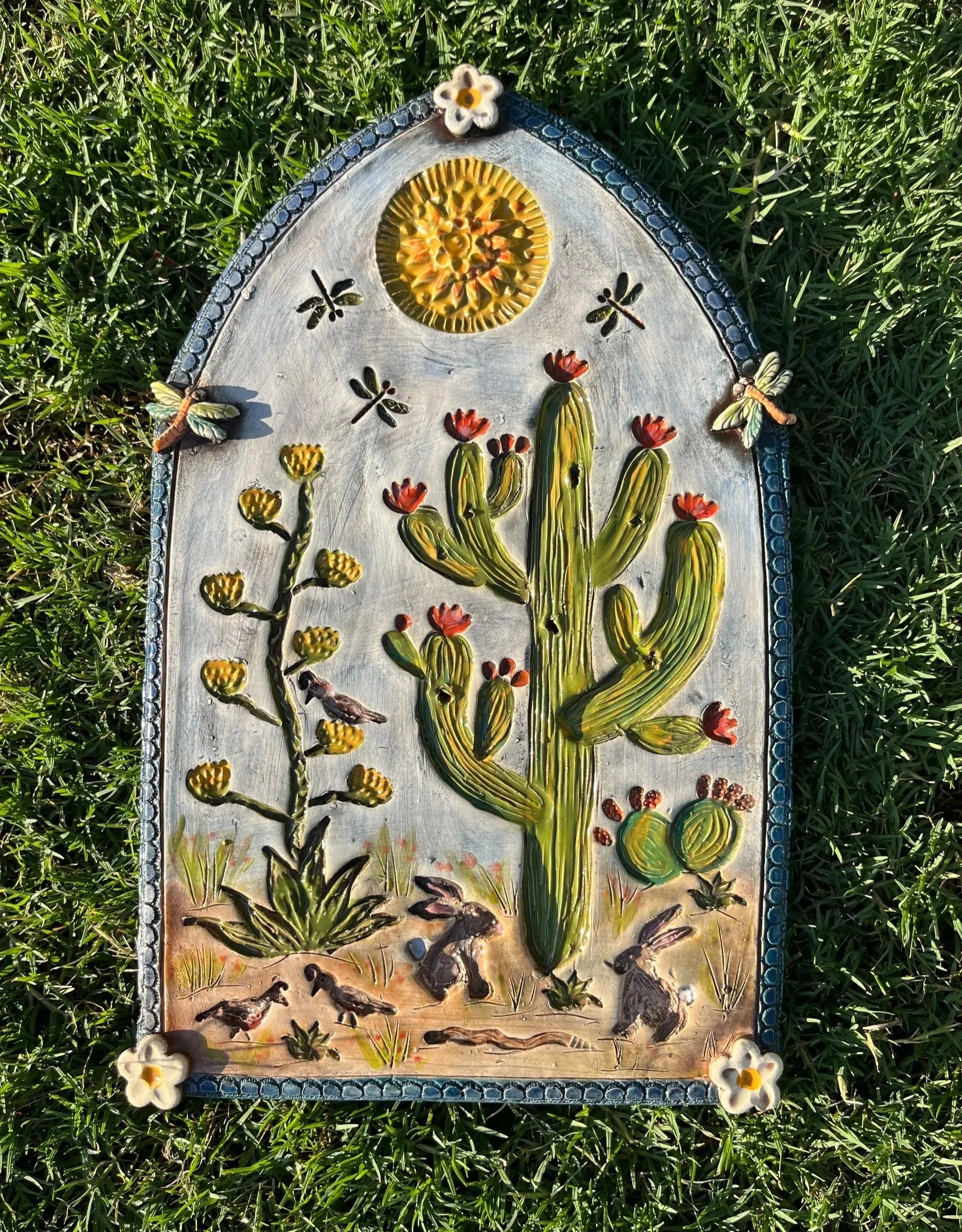 Handmade ceramic plaque featuring Sonoran desert motifs like saguaros and wildflowers, with earthy textures and warm tones from the Sonora Collection by Terrianndavisdesigns.