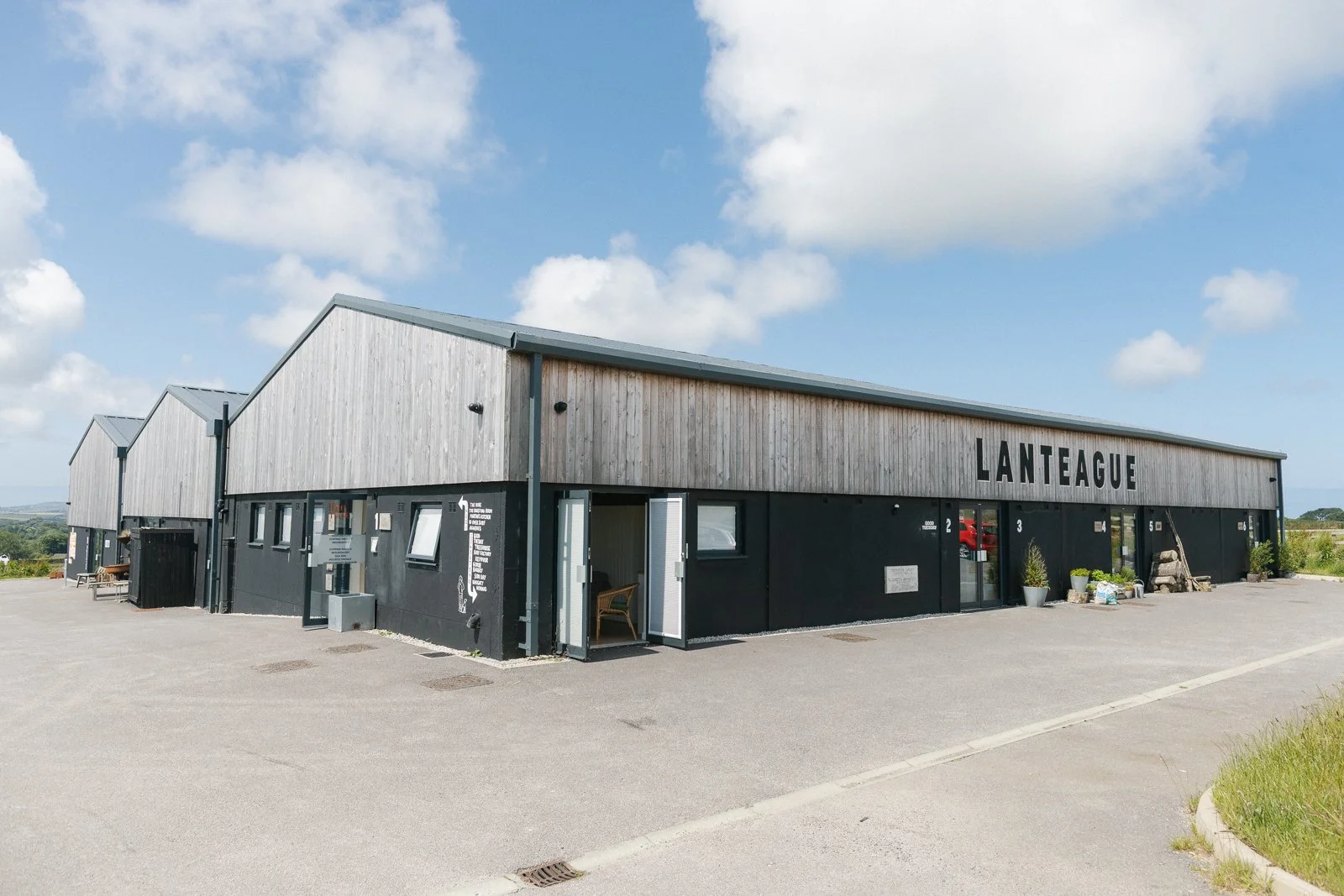 A modern building with a black lower section and a wooden upper section, labeled 'LANTEAGUE', under a partly cloudy sky.