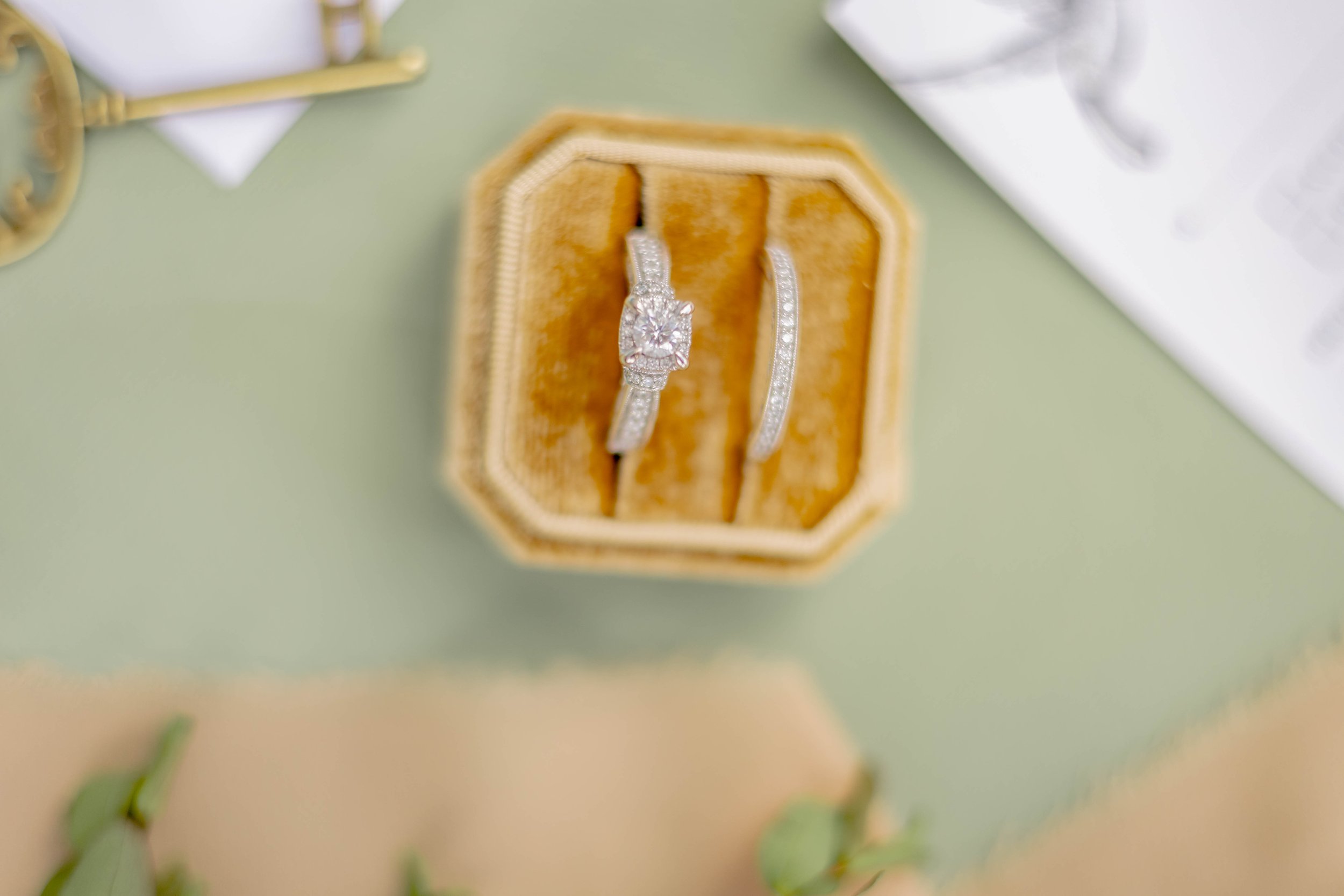 Engagement and wedding ring set in gold box on green background