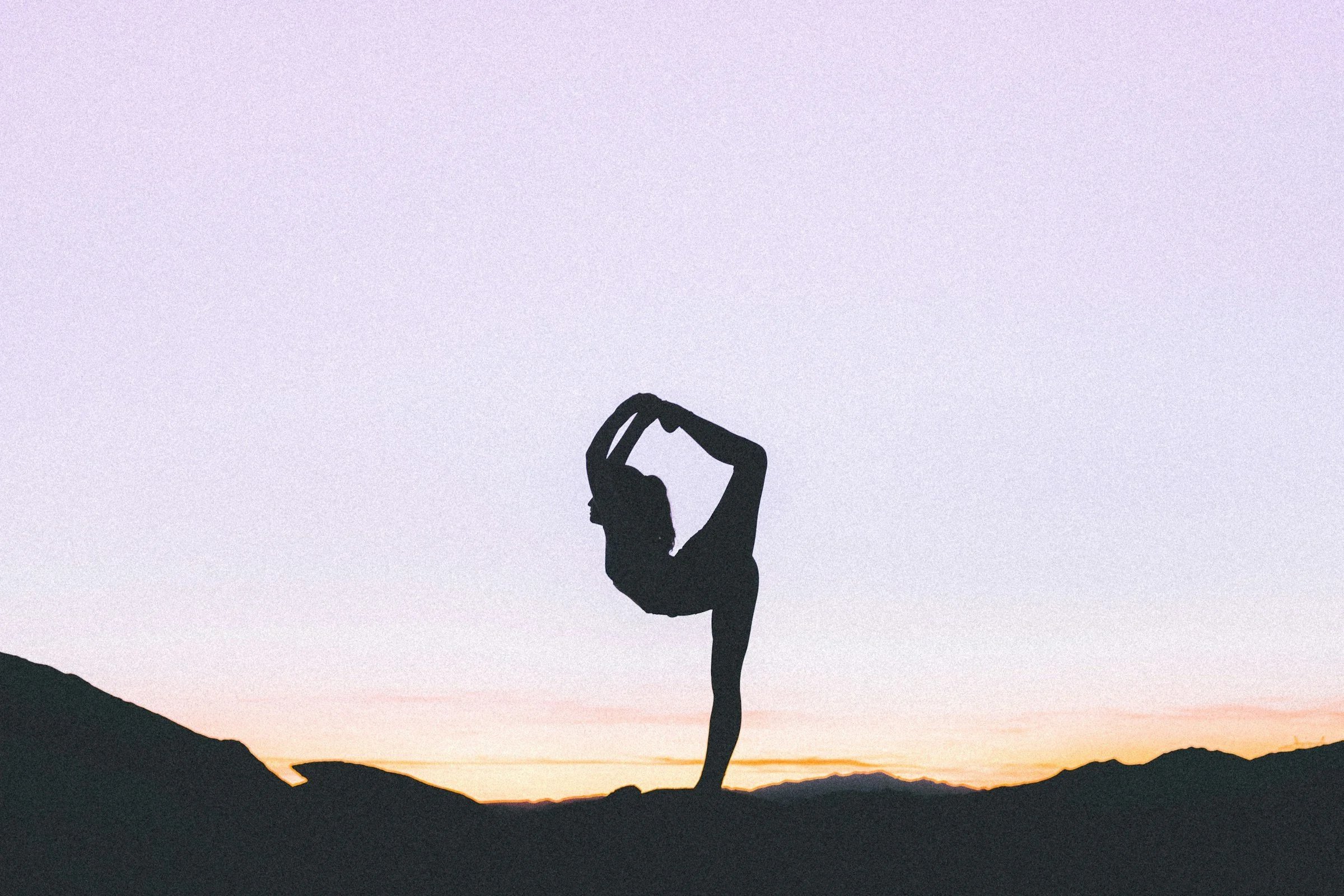 Woman silhouette doing yoga against a sunset