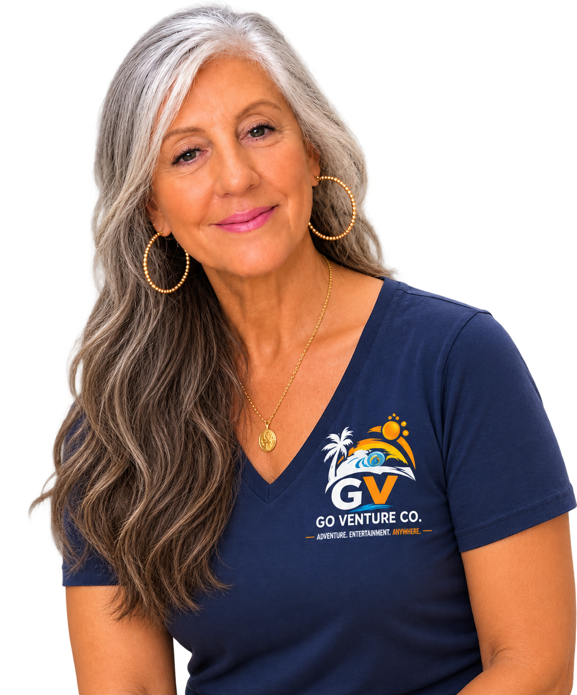 A woman with long gray hair, wearing gold hoop earrings and a gold necklace, smiling, dressed in a navy blue T-shirt with a logo of a tropical scene and the words "Go Venture Co."