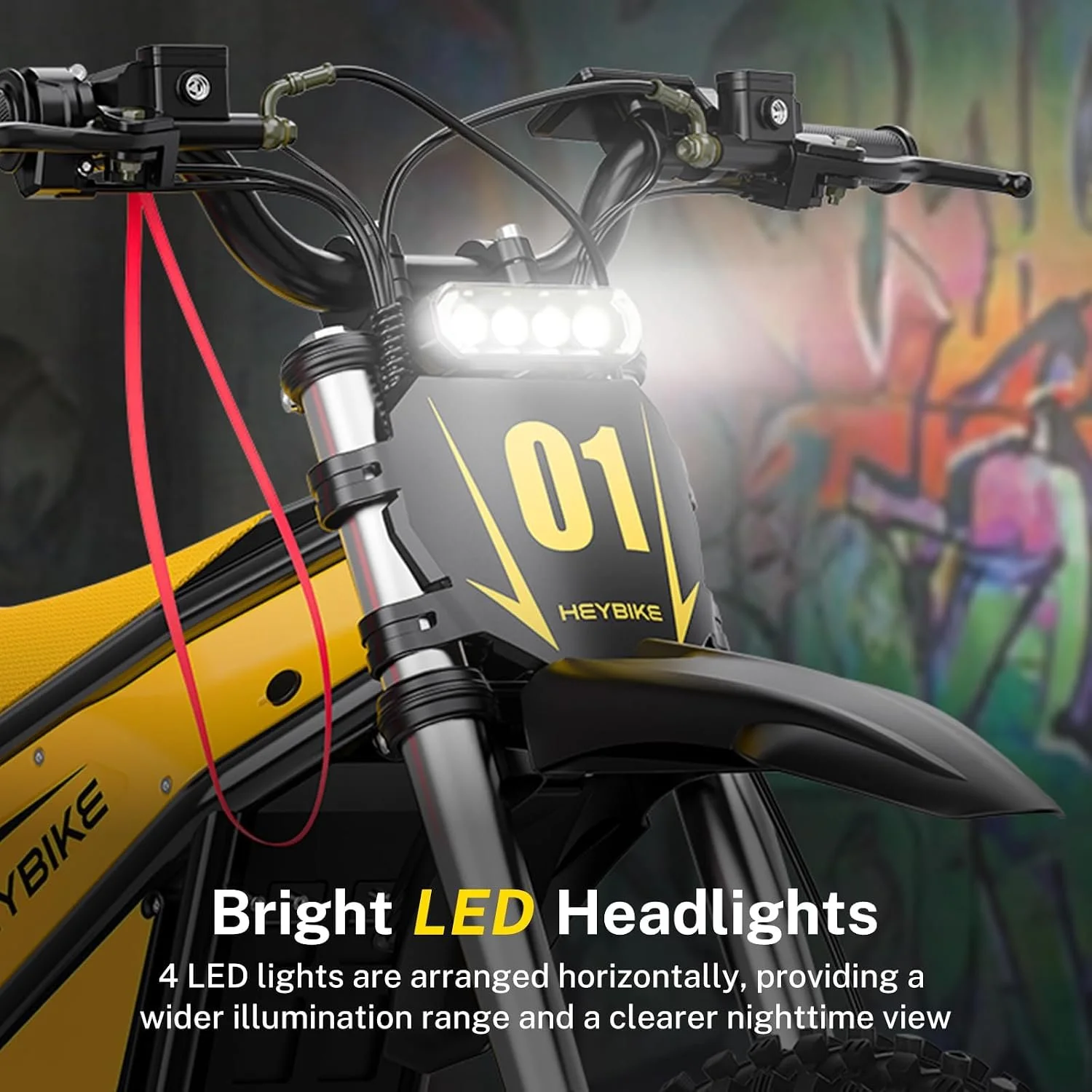 Close-up of an electric mountain bike with bright LED headlights, black handlebars, and a yellow frame, set against a colorful graffiti background.