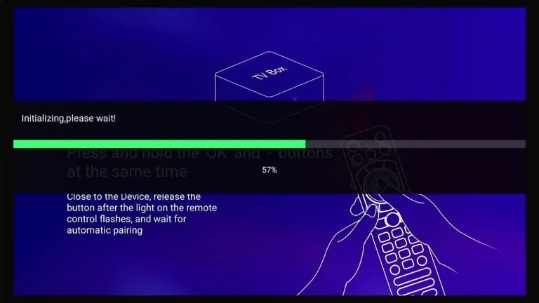 Screen displaying a TV box setup process with a progress bar at 57%, instructions for pairing a remote control, and an illustration of a person holding a remote.
