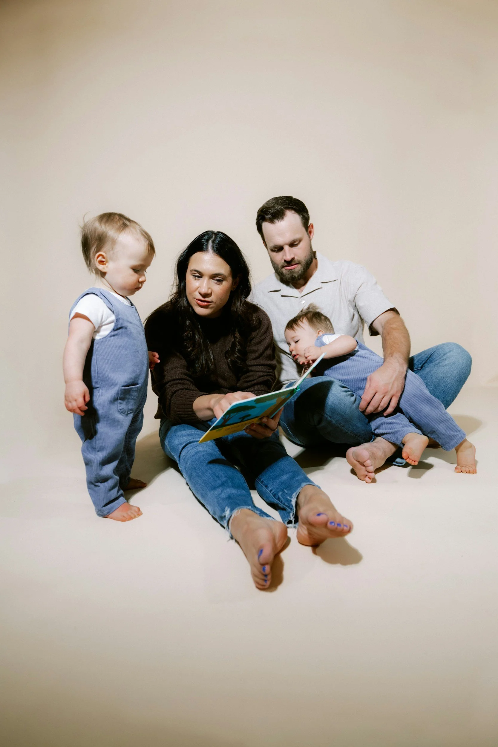 a family of four with two young kids reading a book