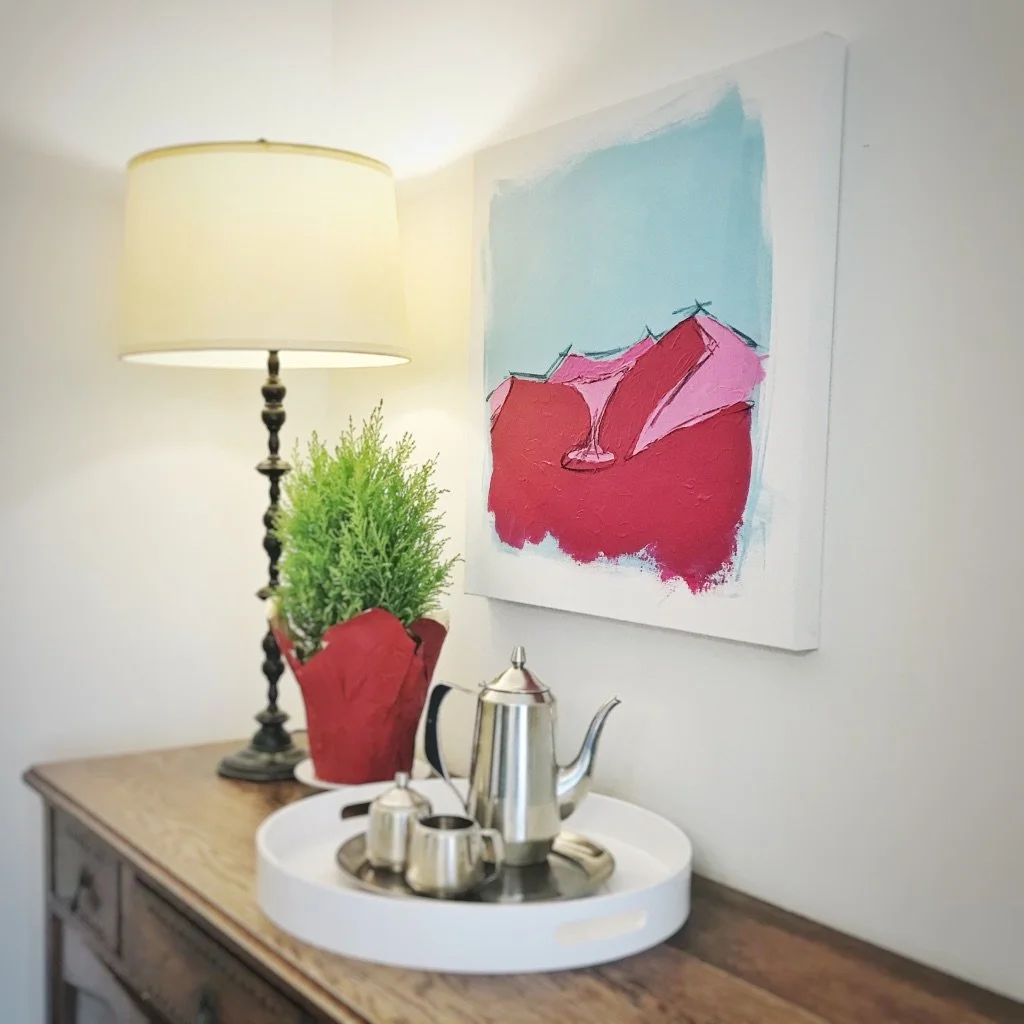 Interior scene with a lamp, abstract painting, potted plant, and a tray with a coffee set on a wooden table.