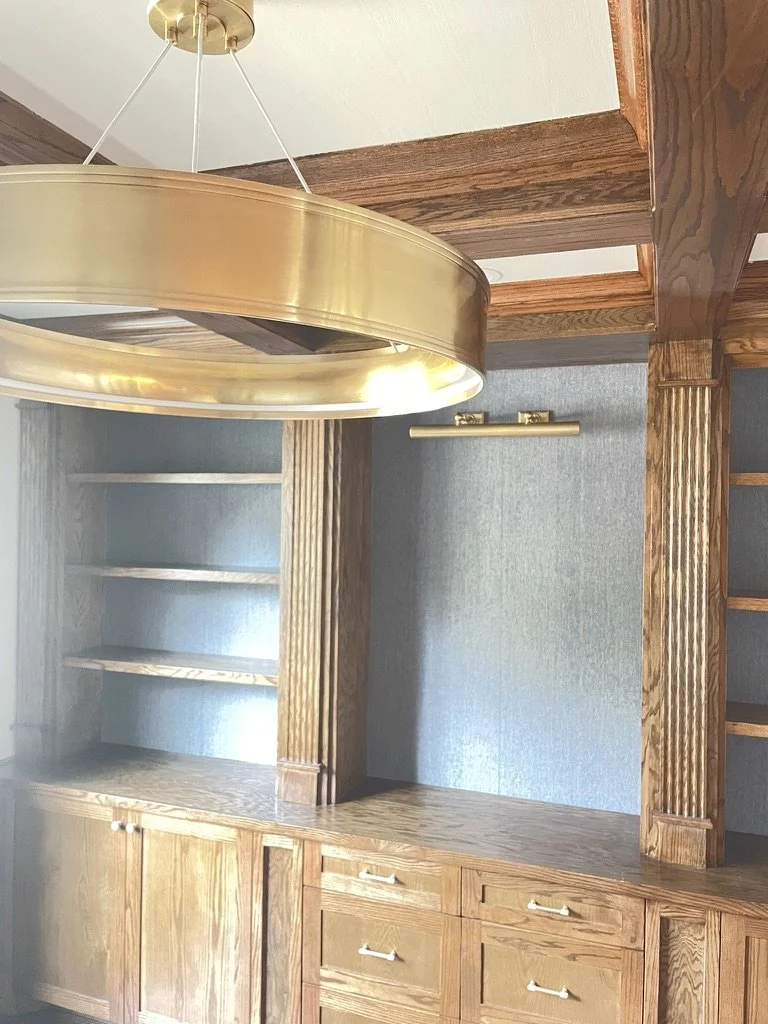 Wooden built-in cabinets with open shelves, brass light fixture, coffered ceiling