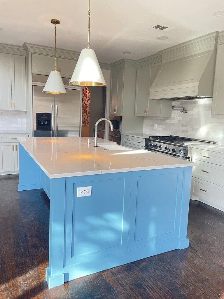 Modern kitchen with light green cabinets and a blue island
