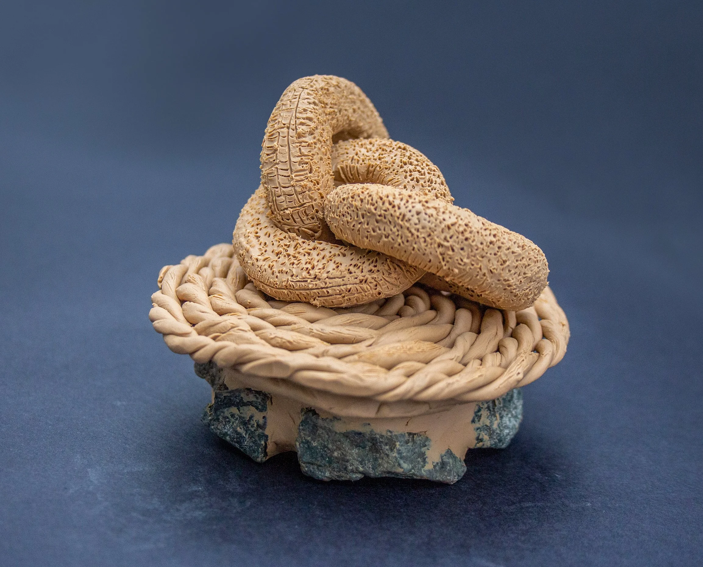 Three beige, textured organs resembling intestines placed on a small, woven, circular basket with a blue background.