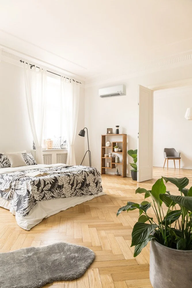 Wall-mounted ductless mini split heat pump installed in a bright bedroom with wooden floors, illustrating indoor heating systems commonly used in Maine homes.