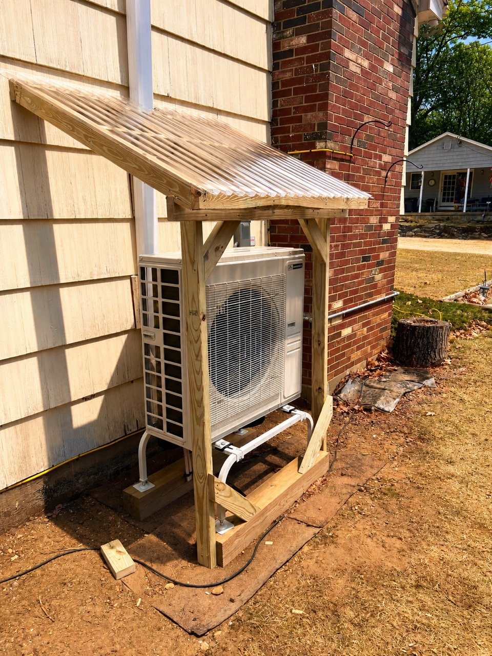 Custom wooden heat pump enclosure installed over an outdoor mini split condenser at a home in Southern Maine to help protect the unit from snow, ice, and weather.