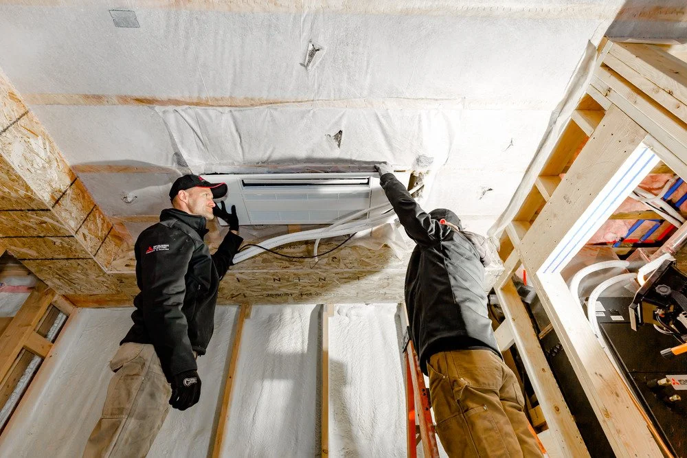 Heat pump technicians installing an indoor unit during a residential heat pump installation in Southern Maine.