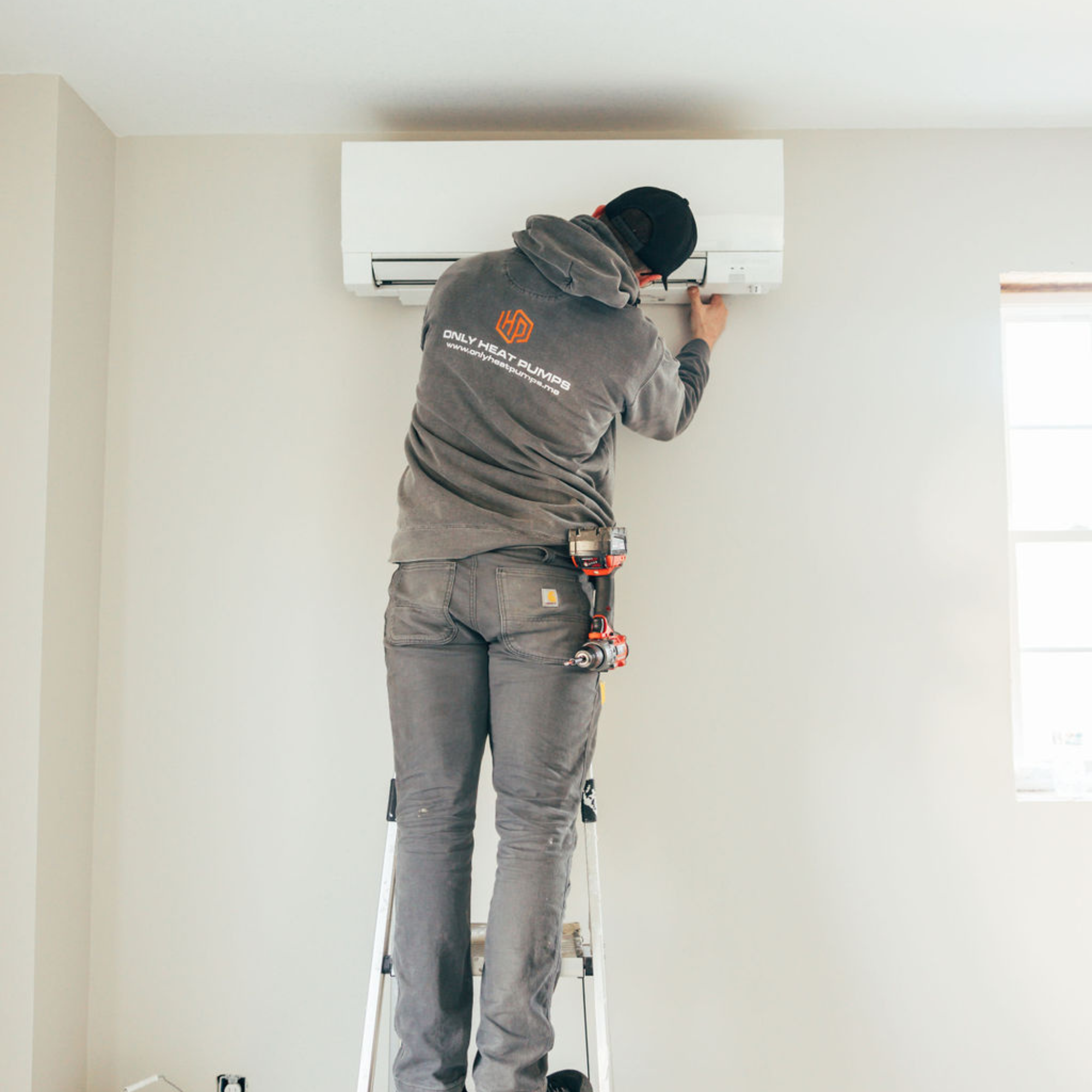 Only Heat Pumps technician cleaning a ductless heat pump in a Maine home