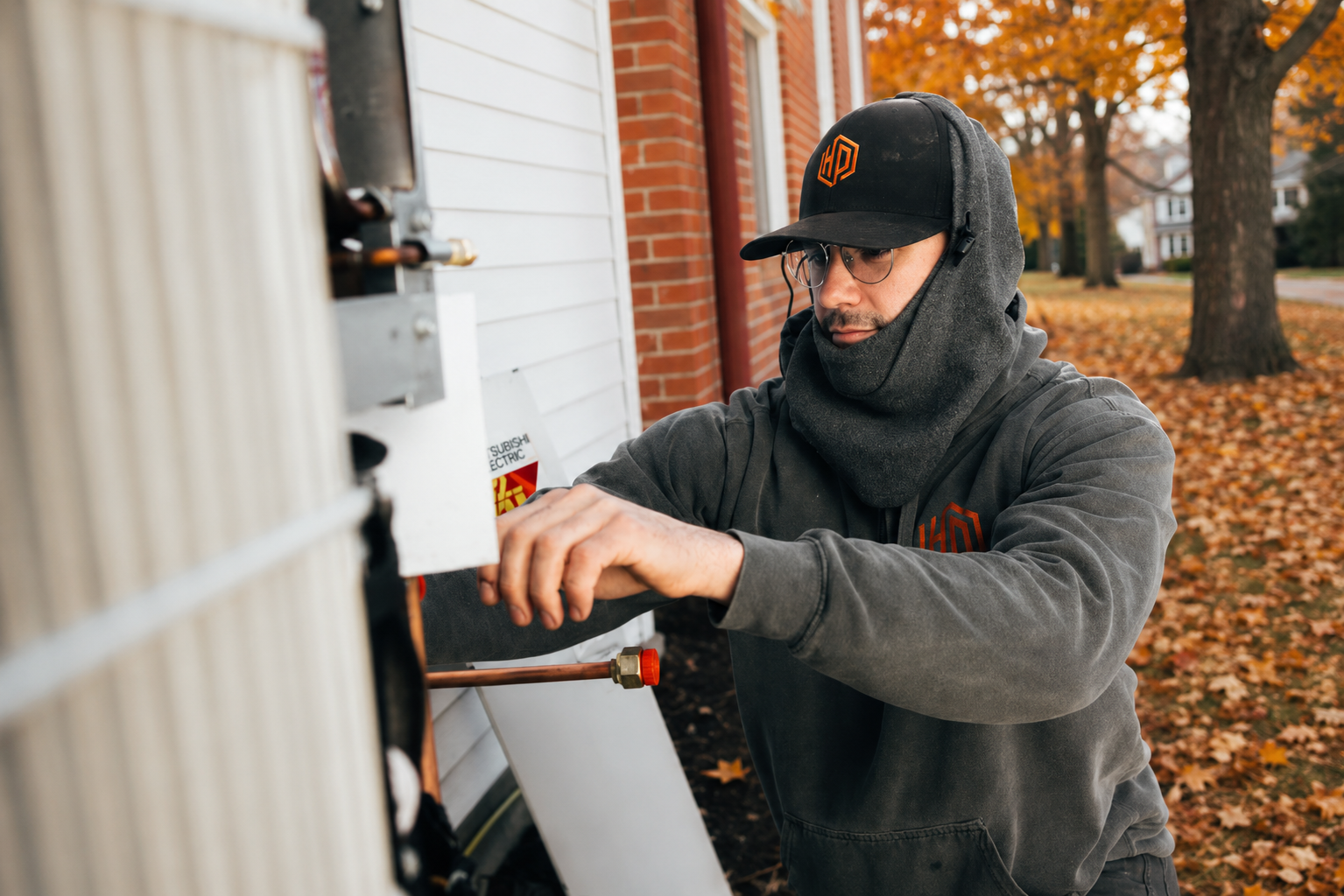 Only Heat Pumps technician inspecting an outdoor heat pump unit during fall in Southern Maine.