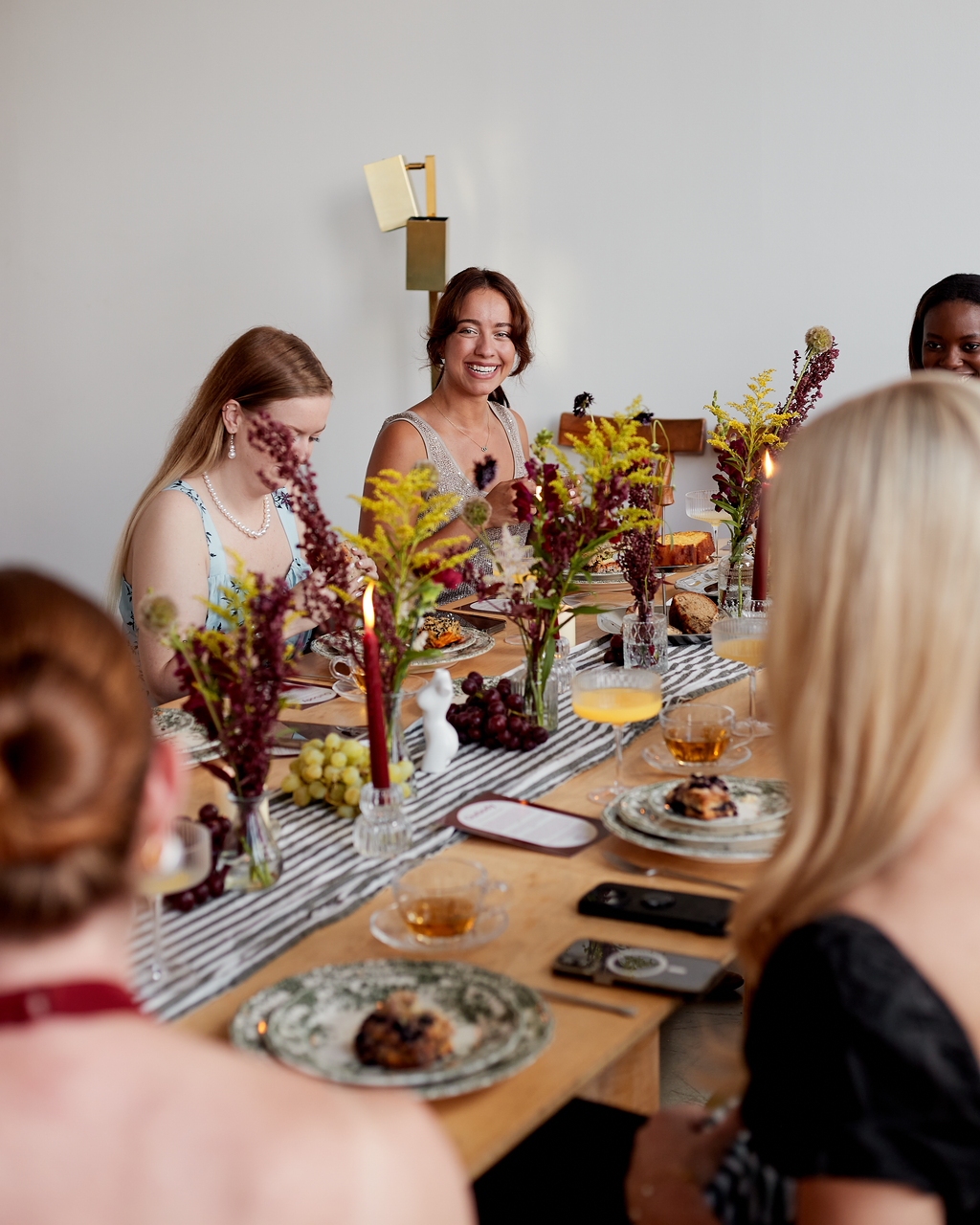 Women gathered around a decorated dining table, smiling and enjoying a meal at a social gathering.
