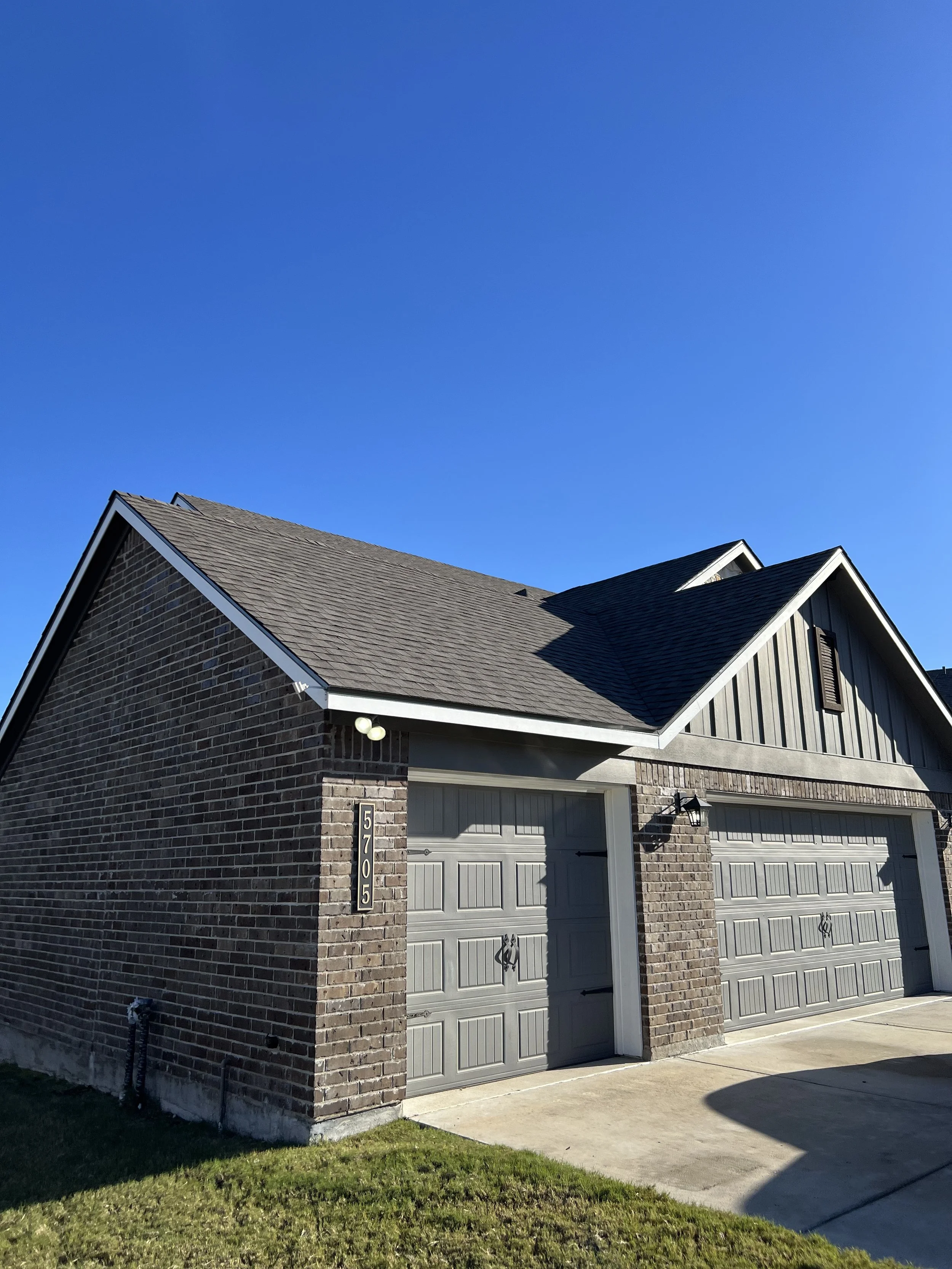 Brick house with twin garage doors under a clear blue sky