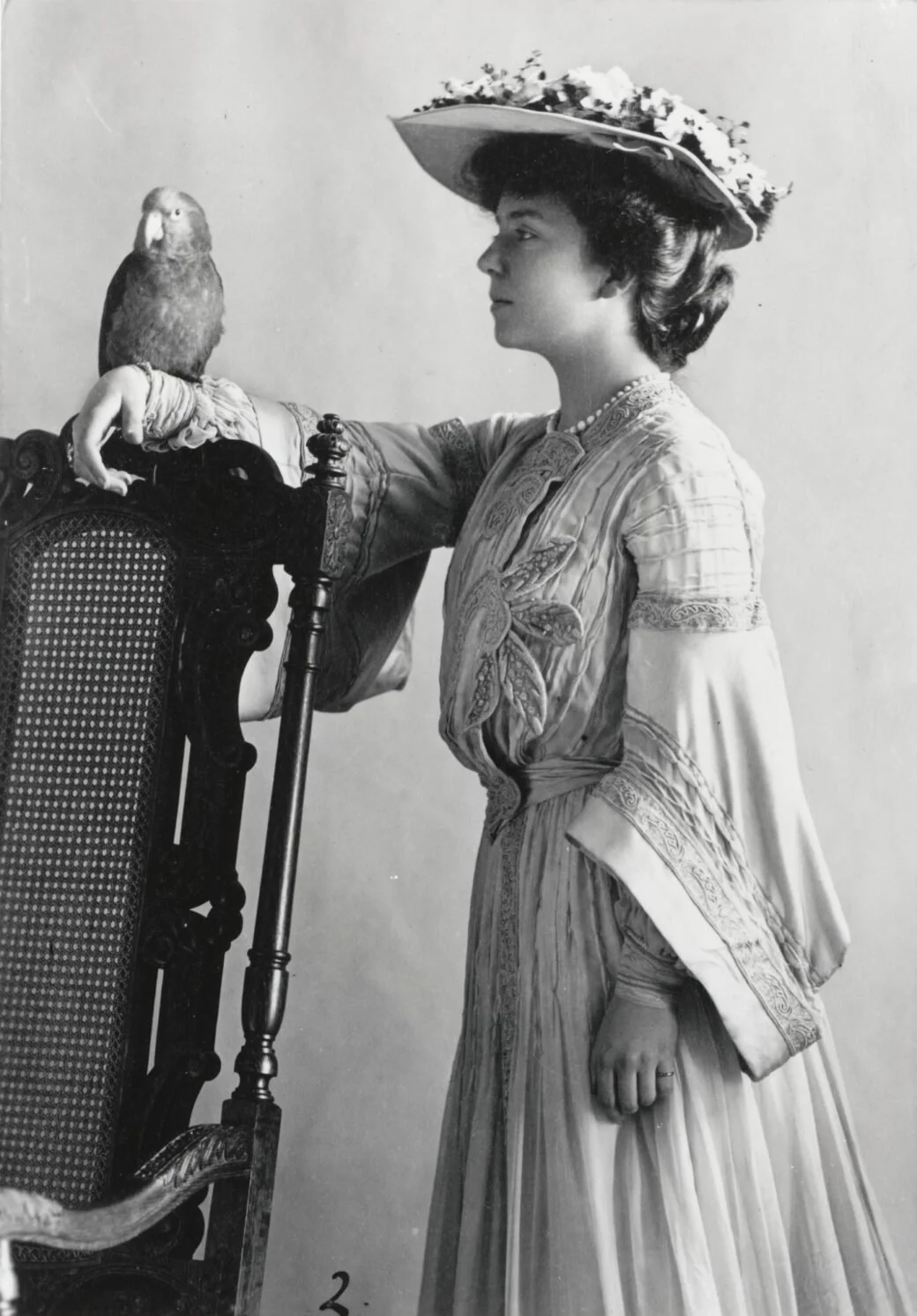 This portrait photograph shows Alice Roosevelt, daughter of President Theodore Roosevelt, posing with a parrot c. 1904.