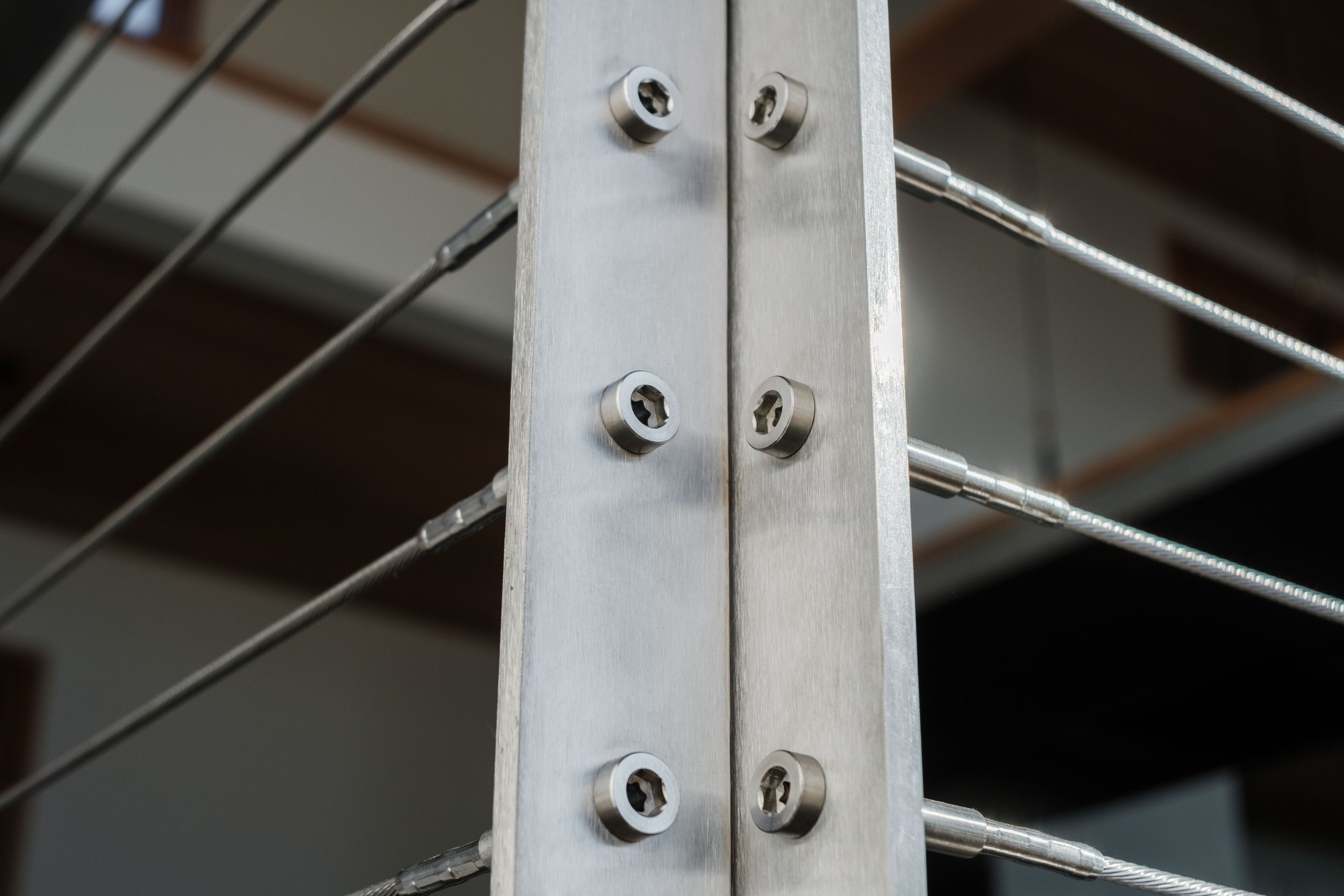 Close-up of a metal railing post with screws in a modern staircase or balcony structure.