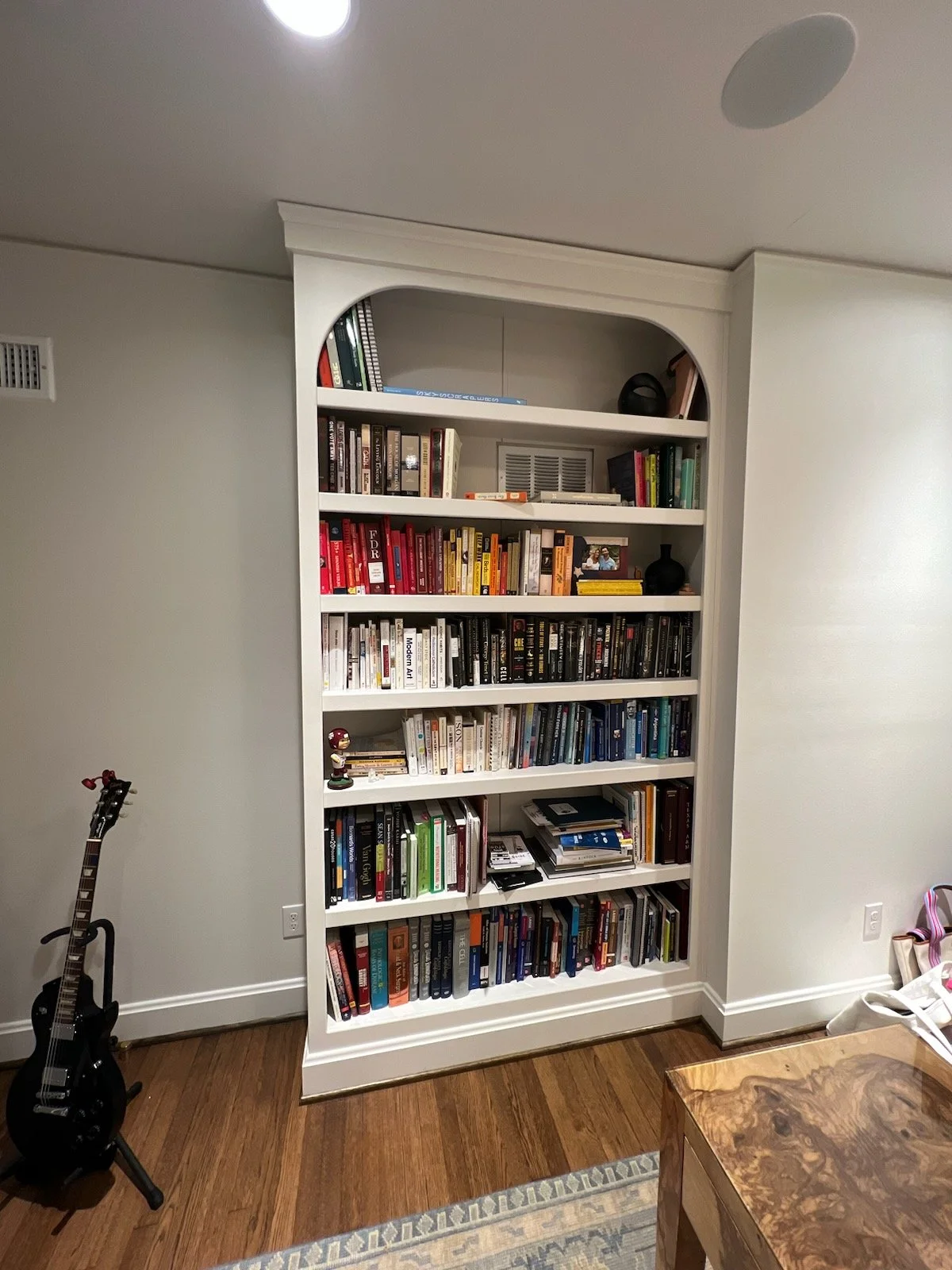 This custom built-in bookshelf is designed to feel architectural, timeless, and completely integrated into the home. Featuring a soft arched upper opening, clean face frames, and adjustable shelving, this piece balances classic millwork details with 