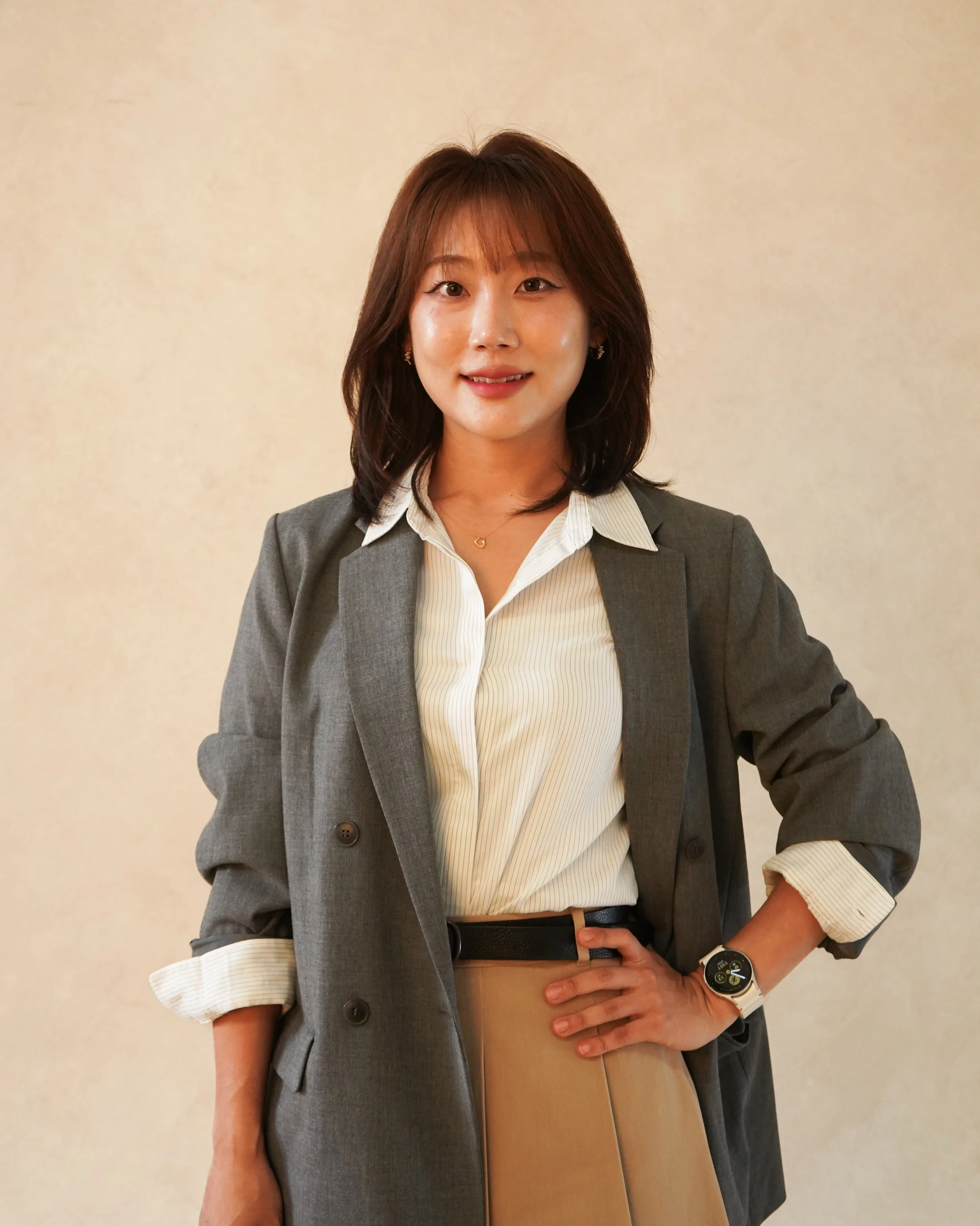 Black and white image of a person smiling while sitting, wearing a suit and white shirt.
