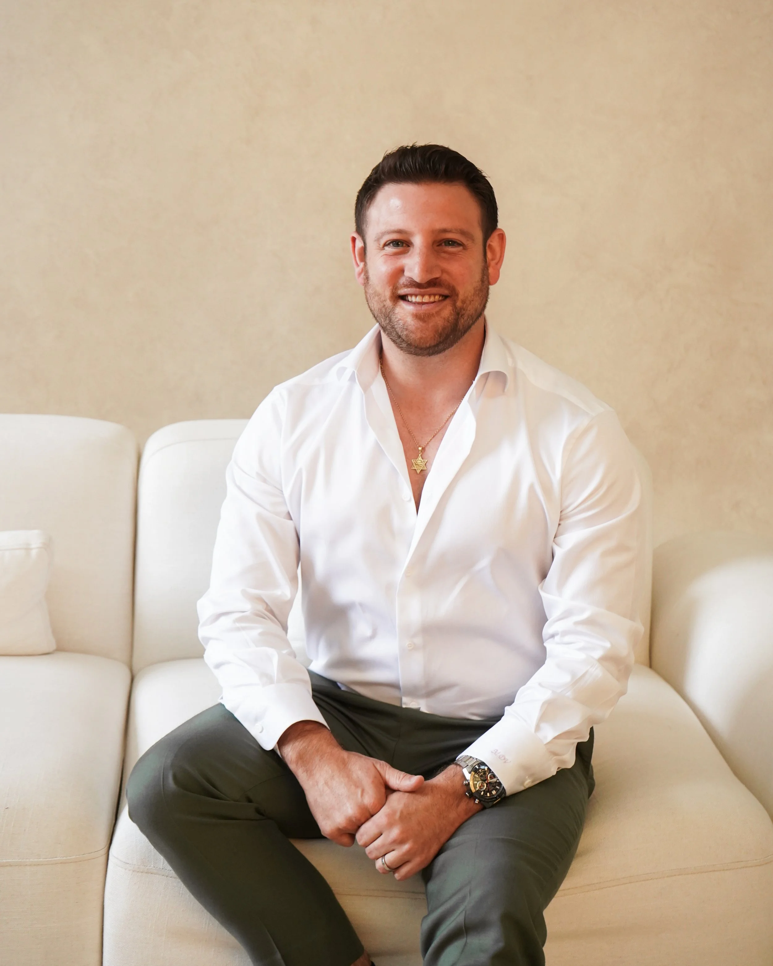 Black and white portrait of a man in a suit sitting on a stool.