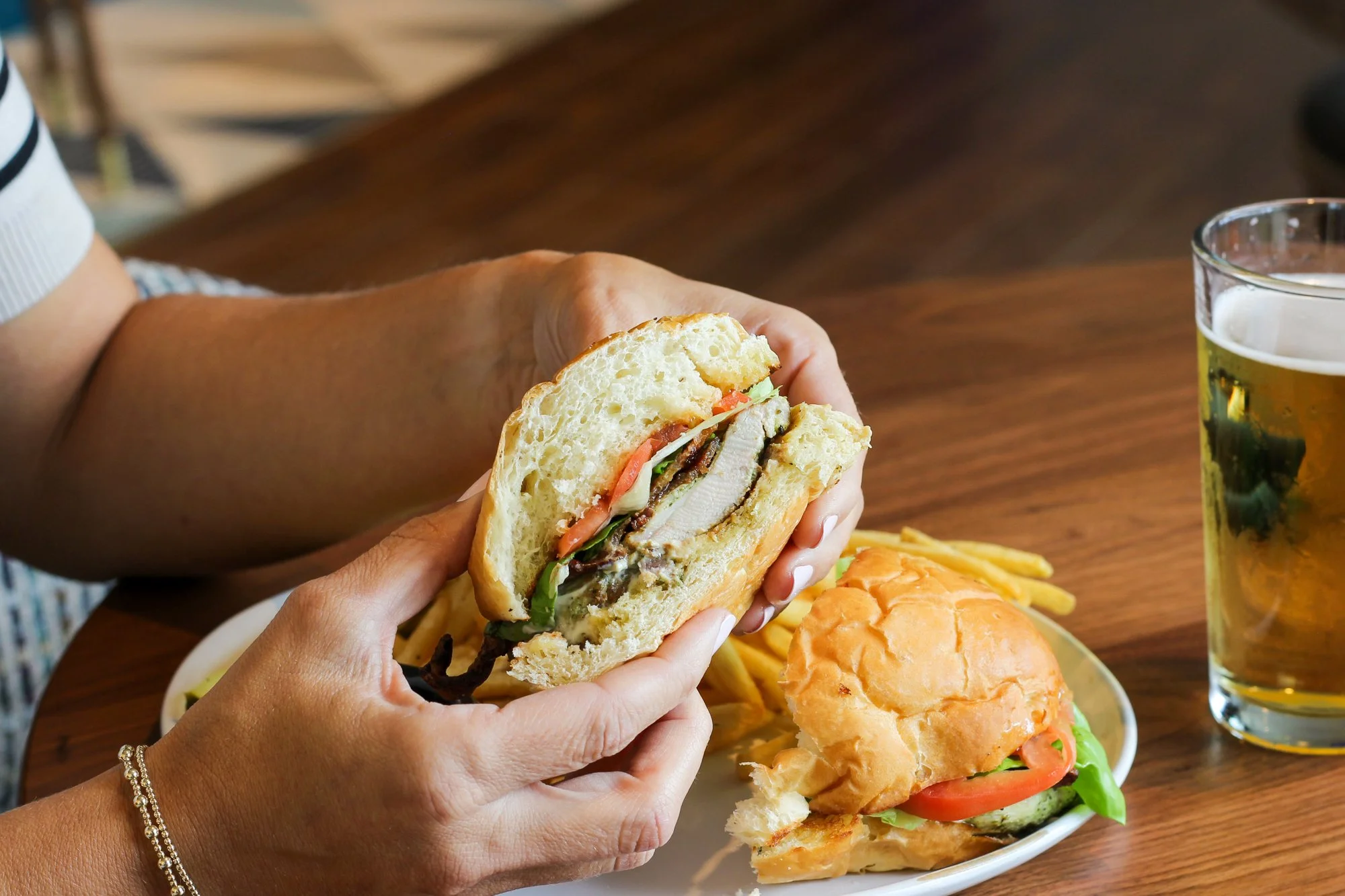Hands Holding Grilled Chicken Sandwich at Harvest Kitchen and Spirits