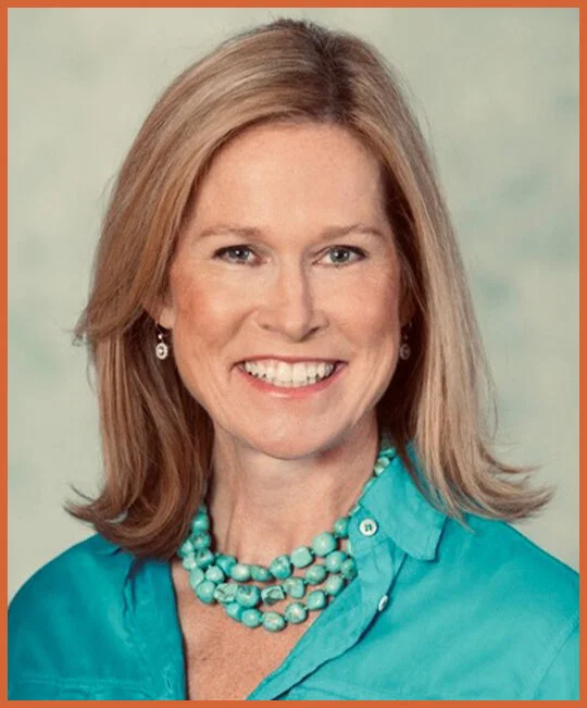 Portrait of a smiling woman with shoulder-length blonde hair, wearing a turquoise blouse and matching pearl necklace and earrings, against a soft green background.