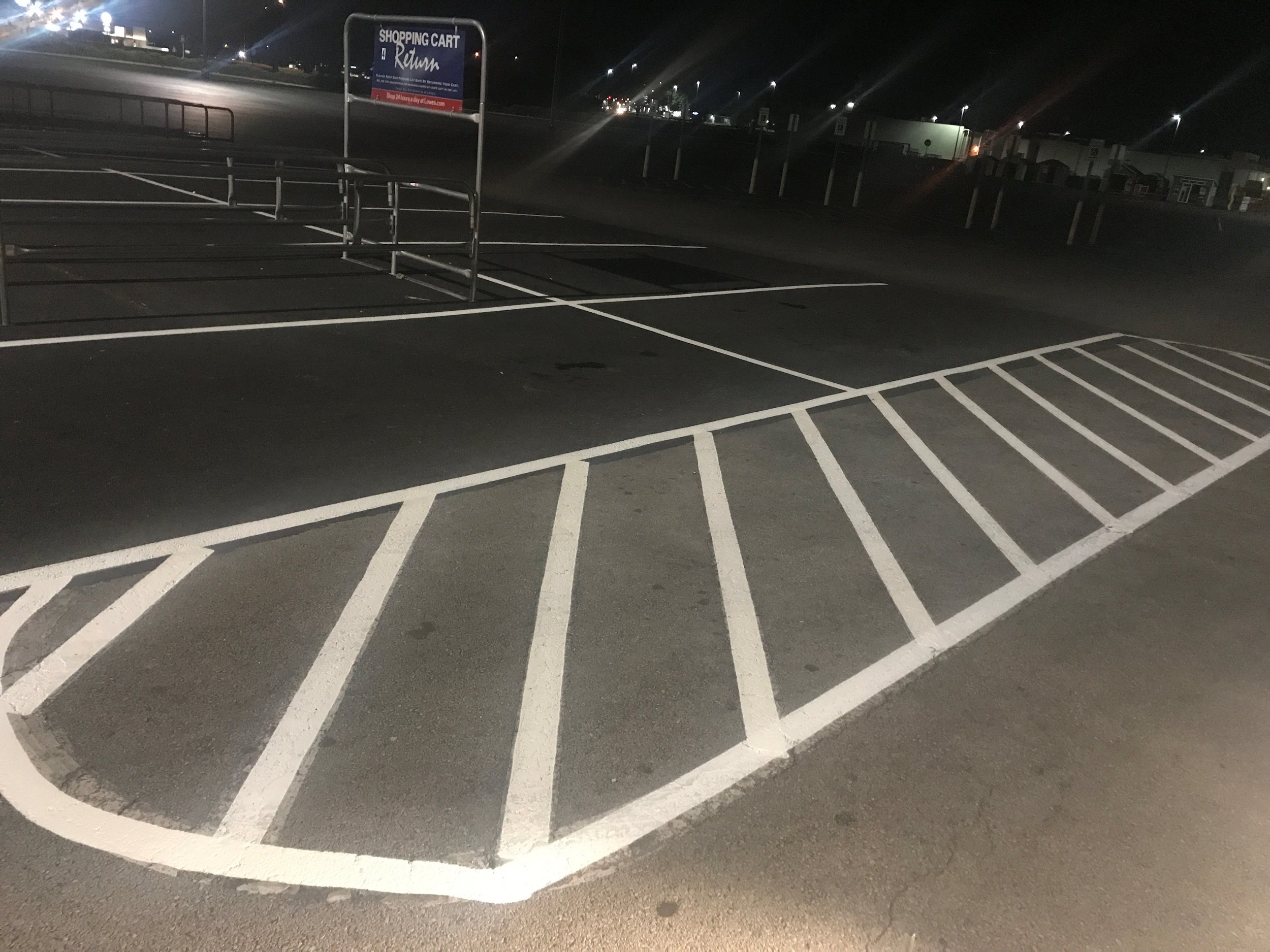 An aerial view of a parking lot with distinct white lines outlining parking spaces.