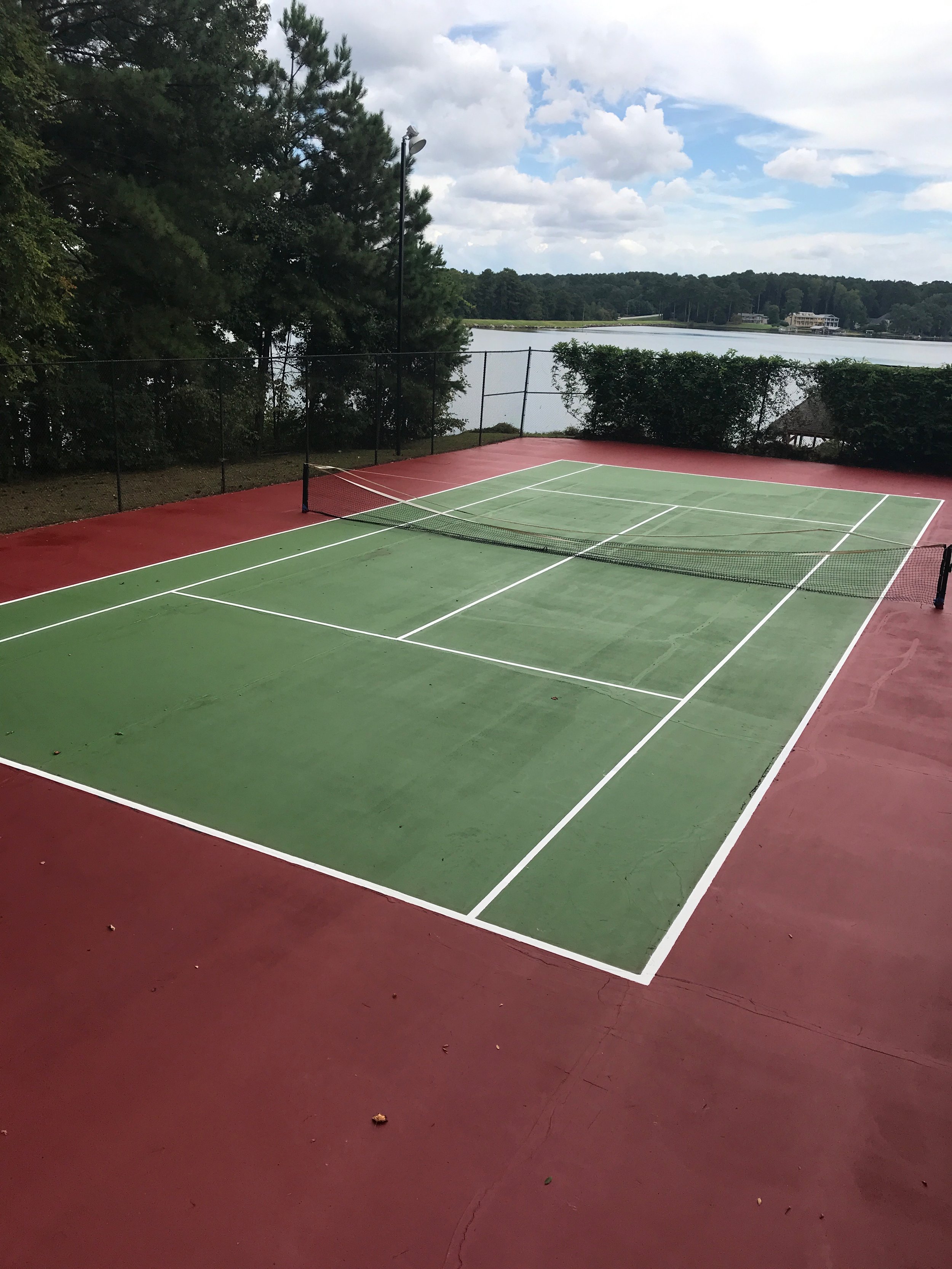 A view of a tennis court with vibrant green and red lines outlining the court boundaries.