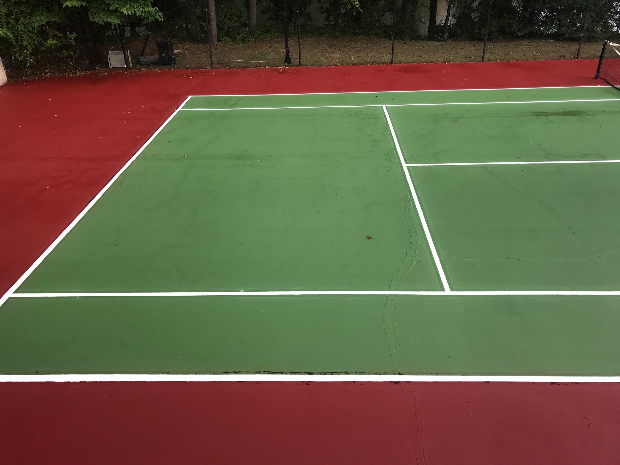 A tennis court featuring a vibrant green surface with red painted lines and markings.
