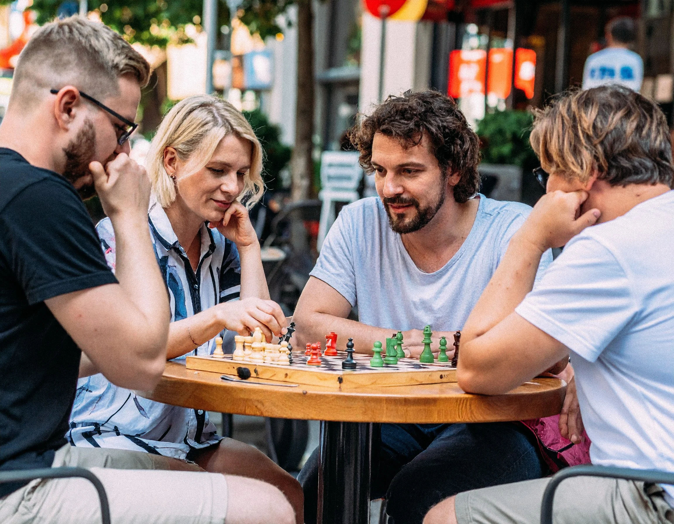 Firefly_Four+people+playing+chess+at+a+table+outside+a+cafe+in+Berlin+in+summer.+859570.jpg
