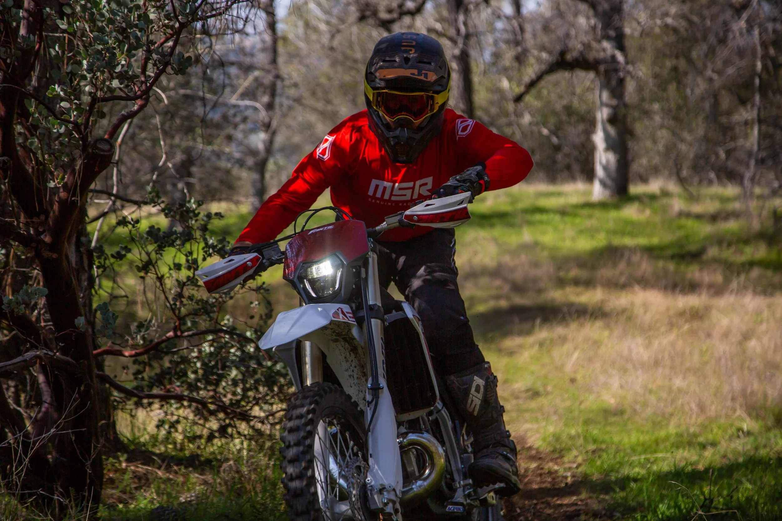 Motorcyclist riding off-road trails through the woods on an enduro dirt bike.