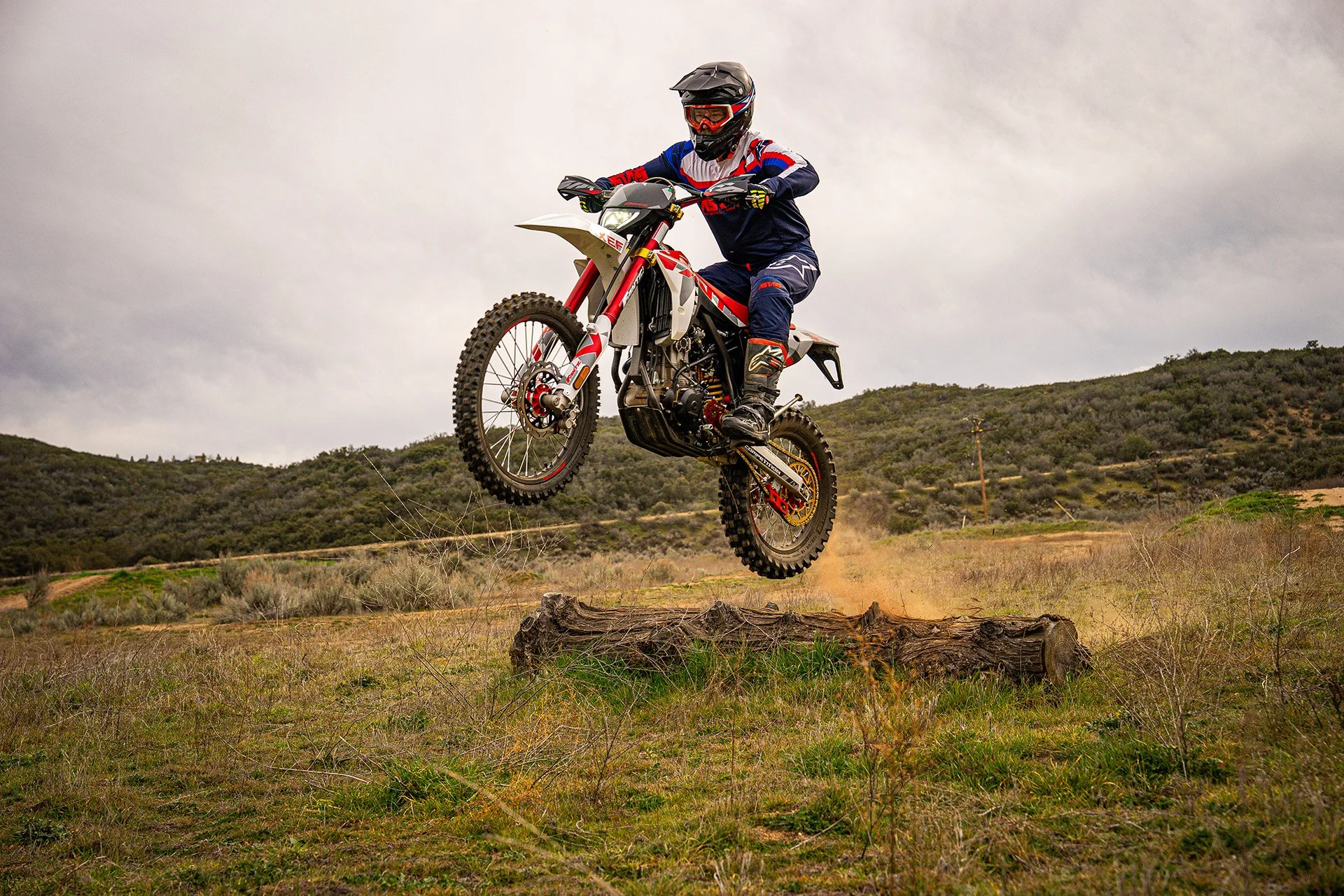 Dirt bike rider launching over a fallen log.