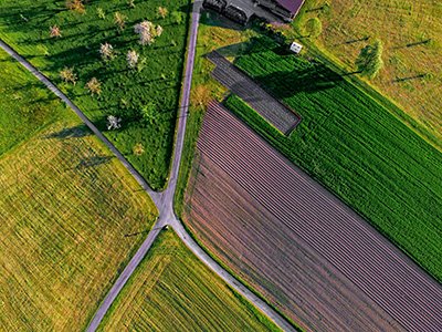 Aerial view of agricultural fields with intersecting roads and different colored crops.