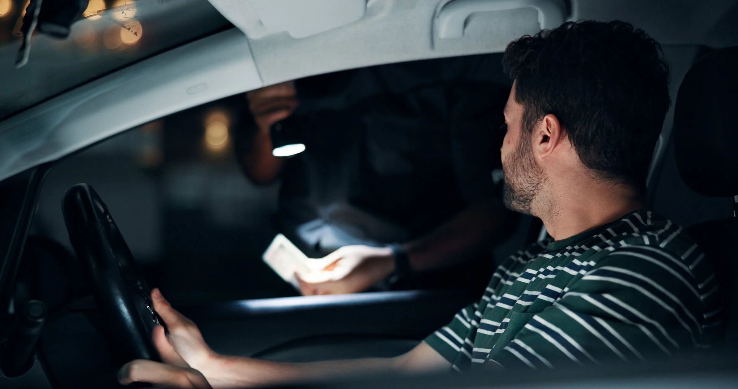 Driver handing documents to a police officer during a night traffic stop in Texas