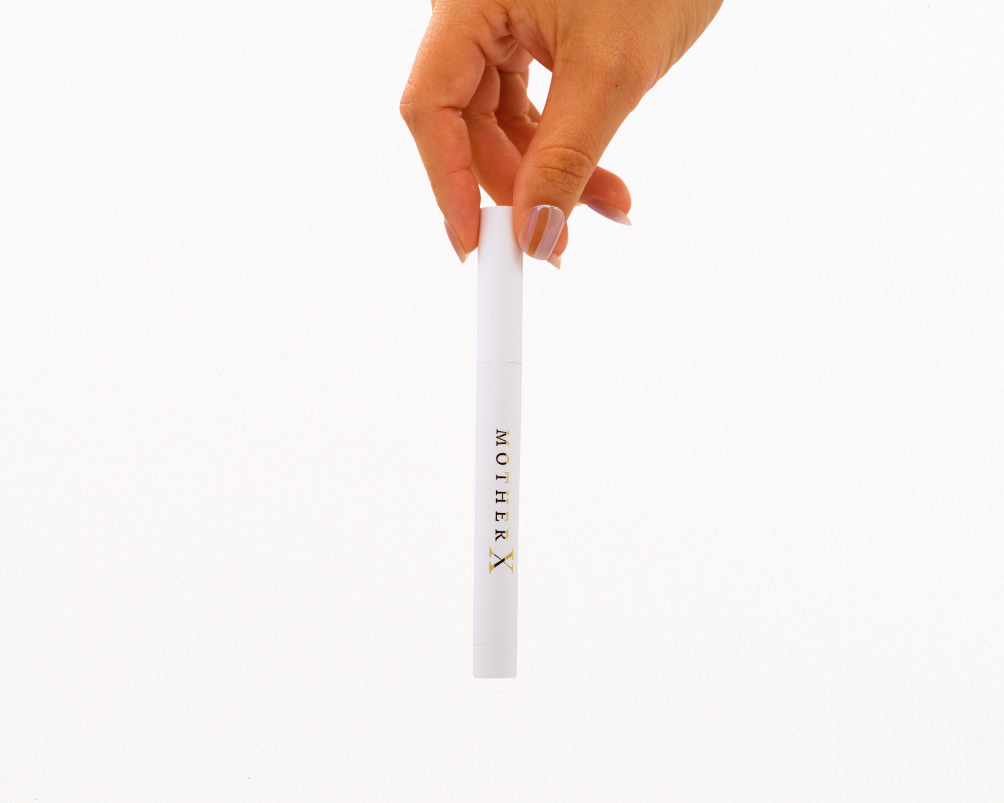 A hand holding a white marker with gold letters that read 'MOTHER X' on a plain white background.