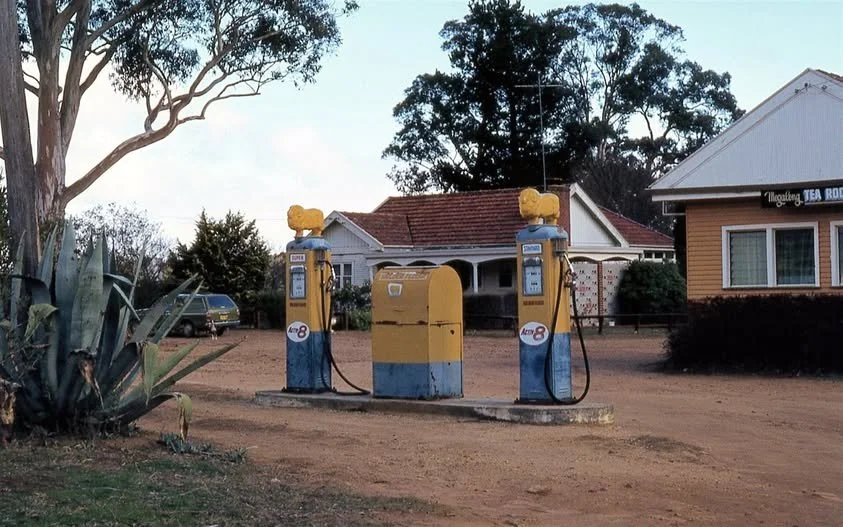 Two vintage Golden Fleece petrol pumps and a yellow mailbox in Megalong Valley, with Tearooms and trees in the background.